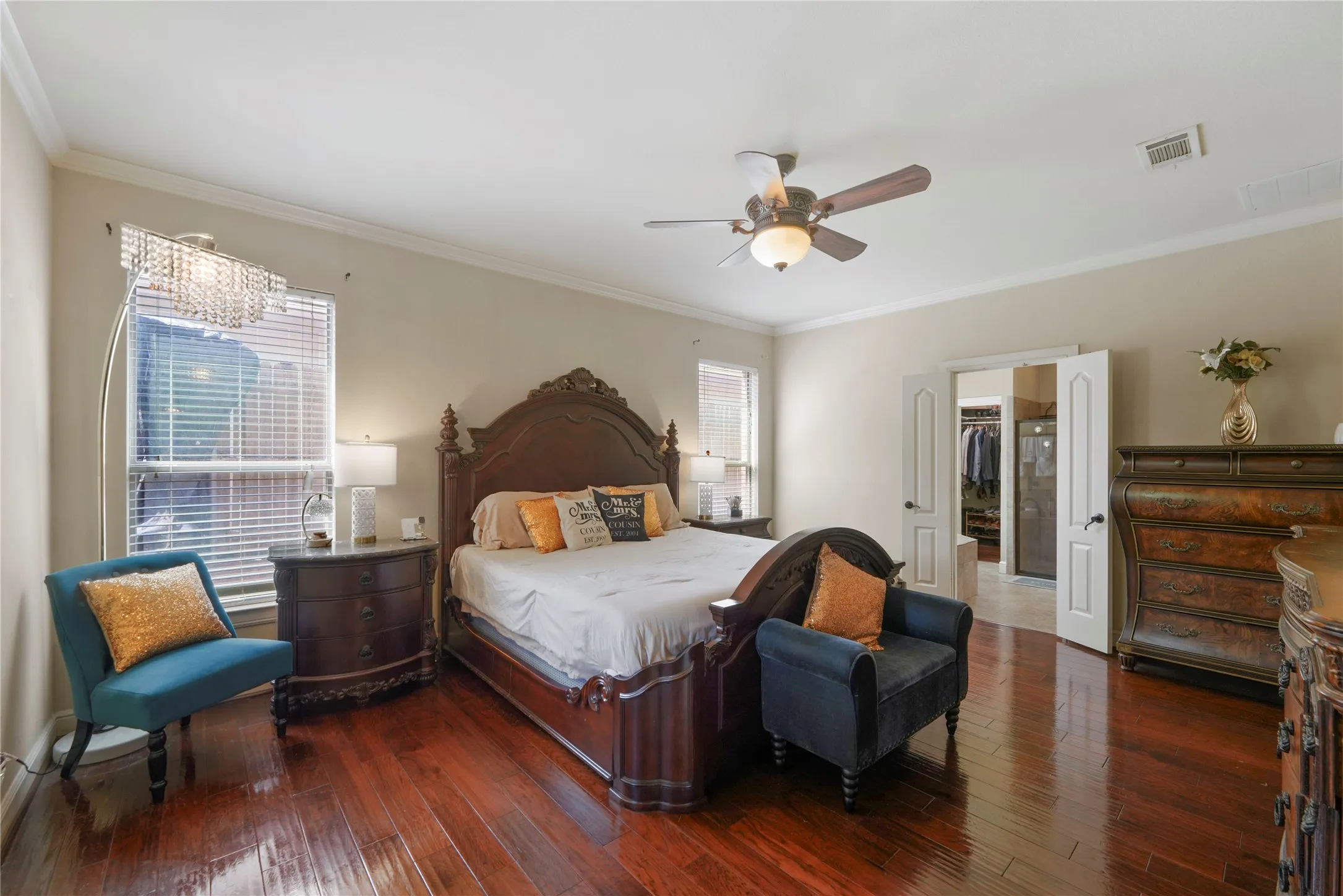 Rich wood-finish flooring, crown molding, and a ceiling fan with integrated lighting