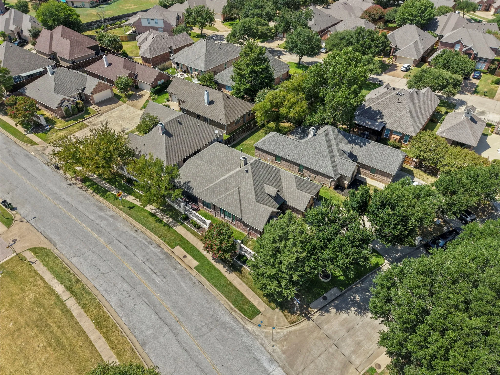 Aerial perspective showcasing a residential area with mature trees and a curvilinear street​​‌​​​​‌​​‌‌​‌‌​​​‌‌​‌​‌​‌​​​‌​​ layout
