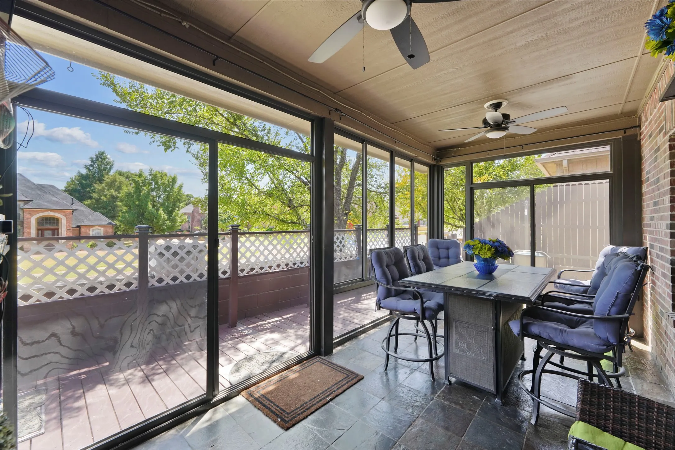 Screened porch featuring ceiling fans, tile flooring, and brick wall accents