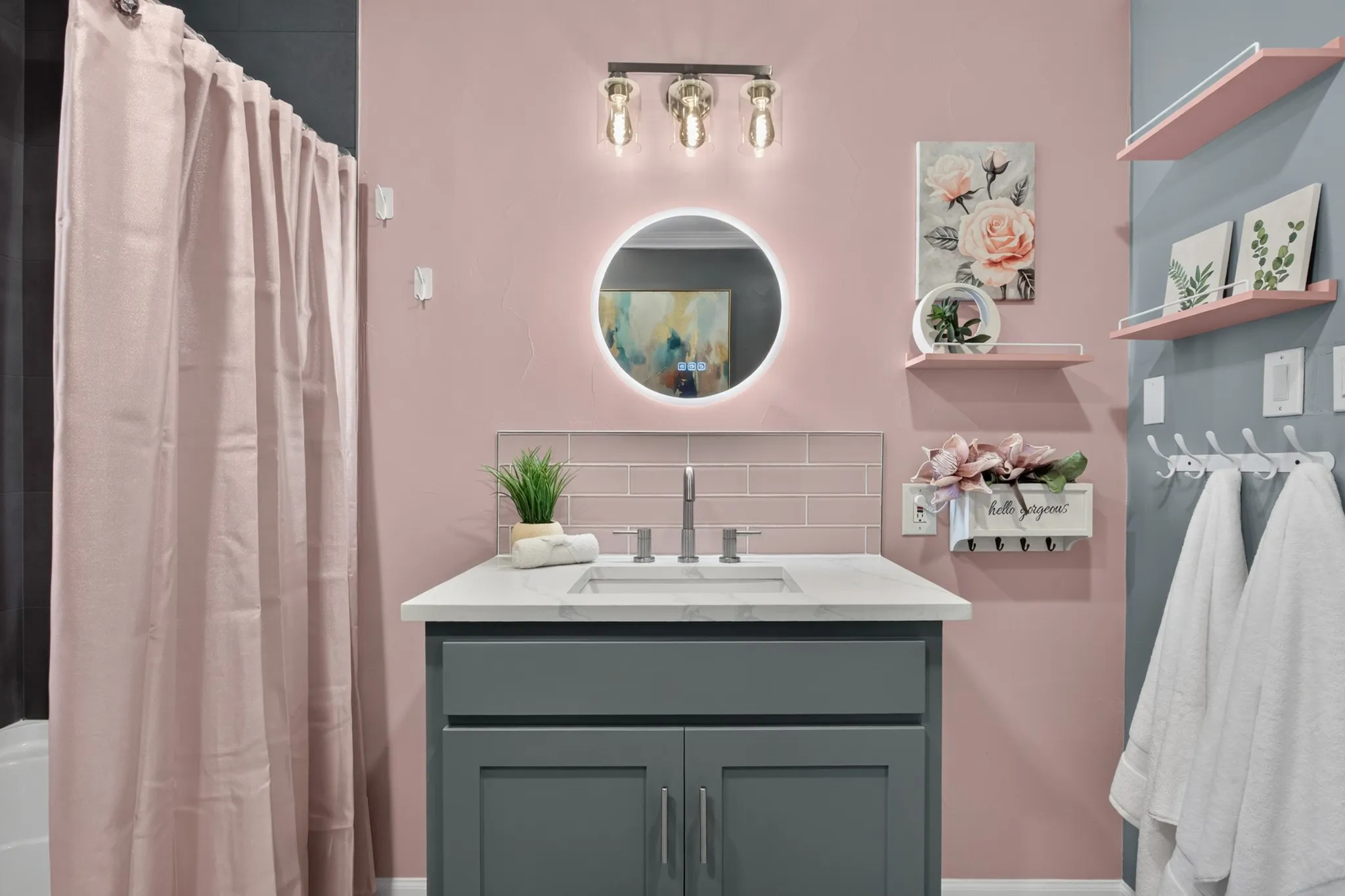 The third full bath, close to bed #3 is pretty in pink with pink glass subway tile accents, backlit mirror, charcoal designer tile surround with rain shower and built ins.