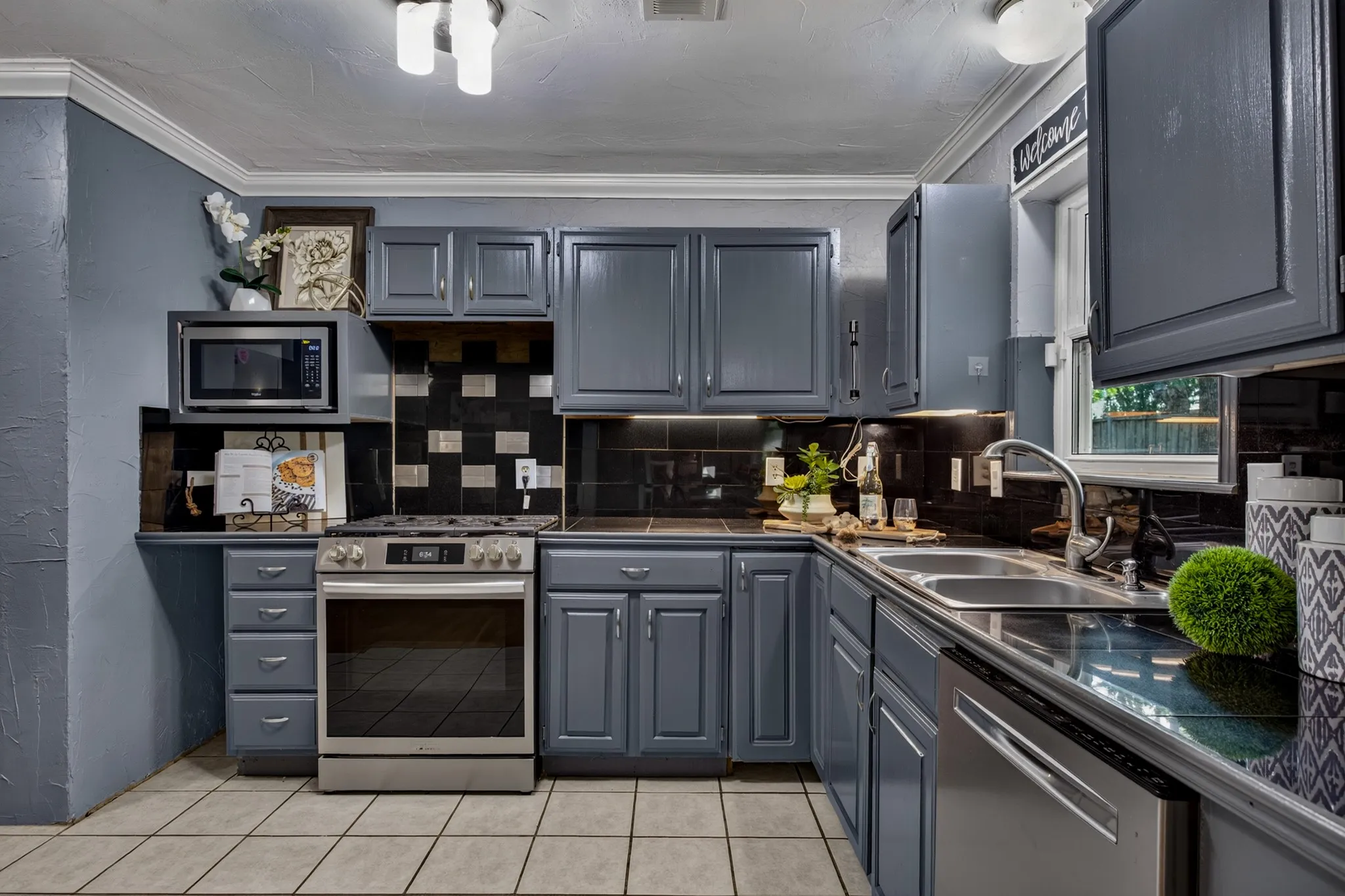 The kitchen is designed for gathering with gray cabinetry, tile countertops and backsplash, stainless steel appliances and gas cooktop, a Frigidaire dishwasher and a refrigerator that conveys with the home. A space perfect for moving in and enjoying or customizing it to make it your own.