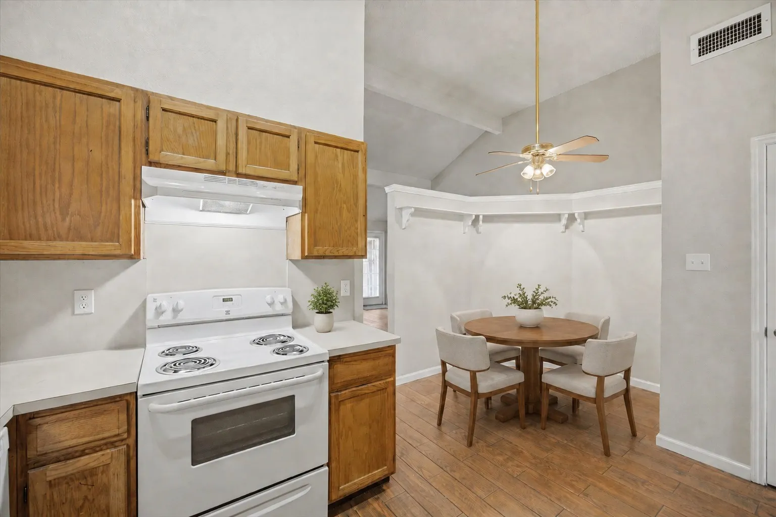 Wood-finish flooring with vaulted ceilings, recessed wall shelving, and a ceiling fan with integrated lighting
