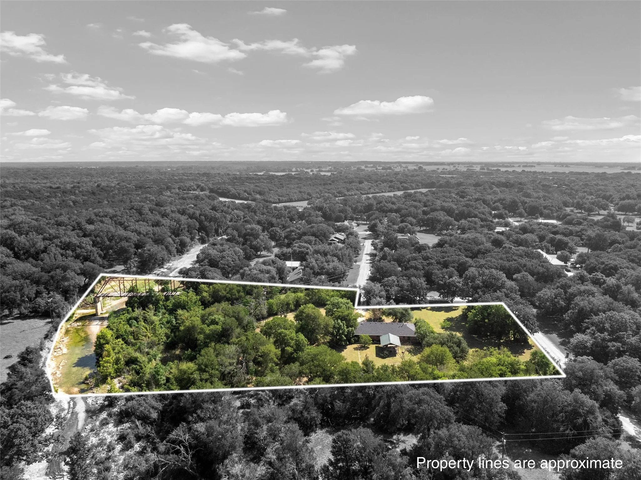 Expansive property featuring a single-story residence, extensive tree coverage, and direct water frontage