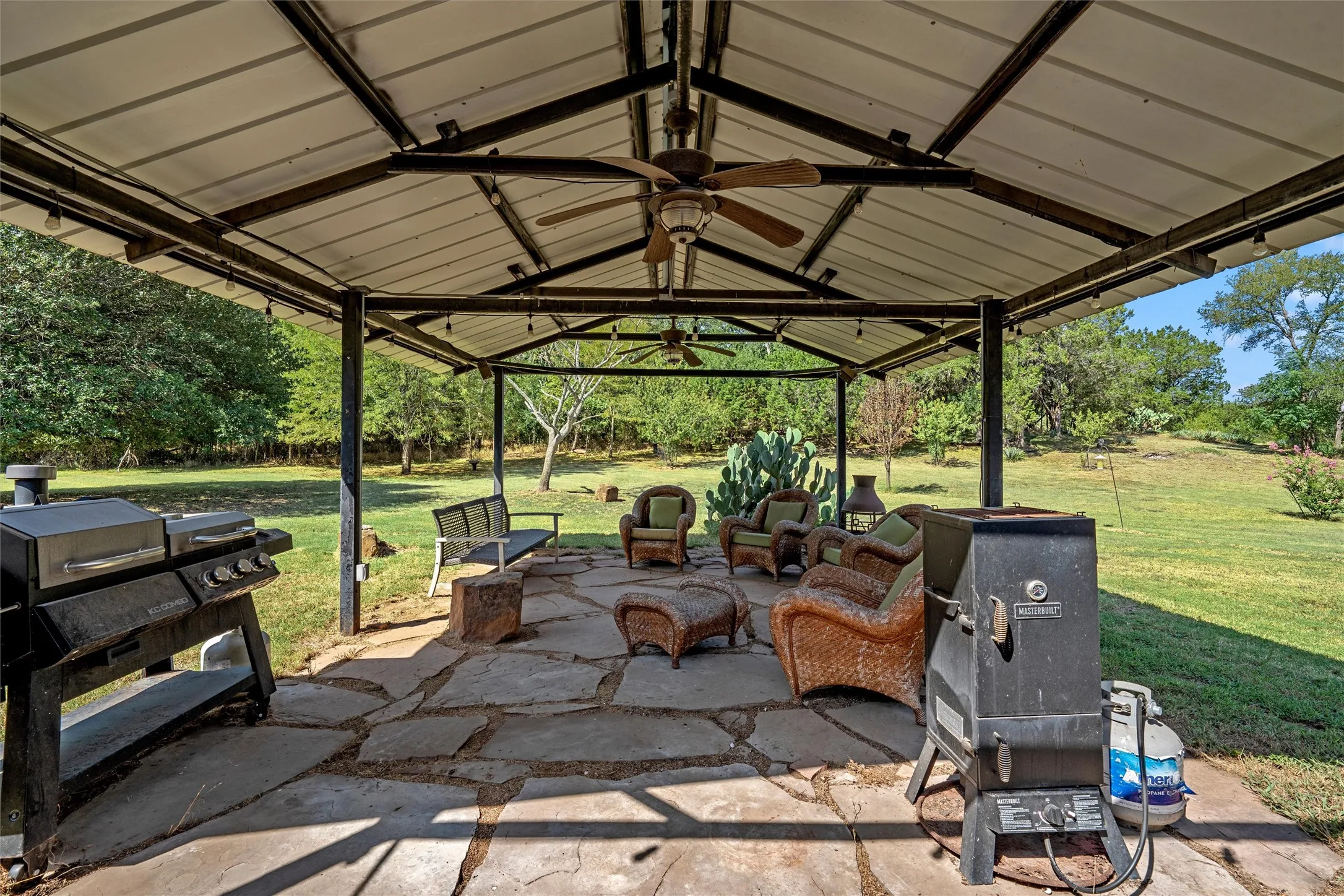Expansive covered patio featuring a metal roof structure, flagstone paving, and a ceiling fan