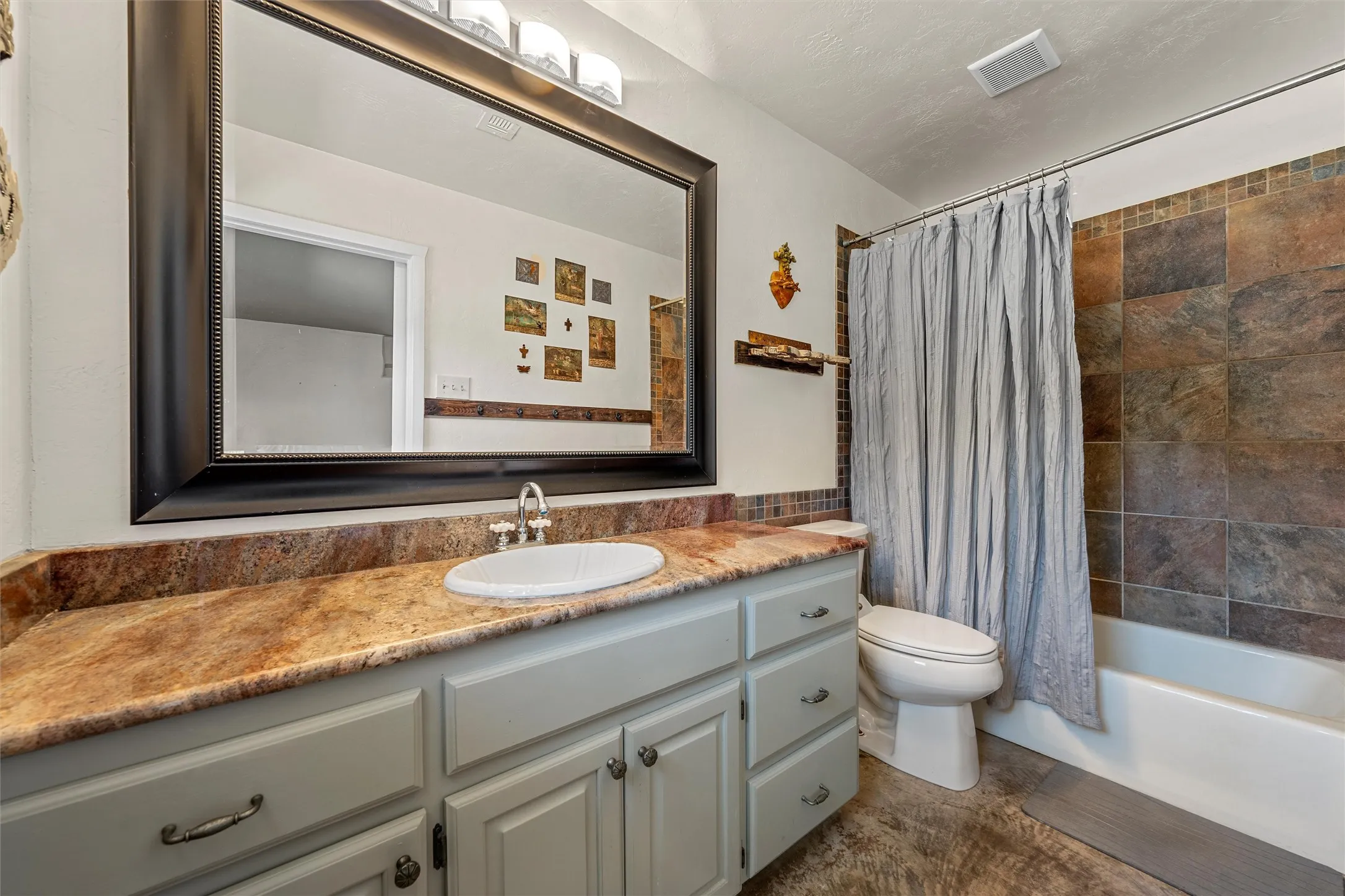 Integrated vanity with a vessel sink, light-toned cabinetry, and an expansive mirror