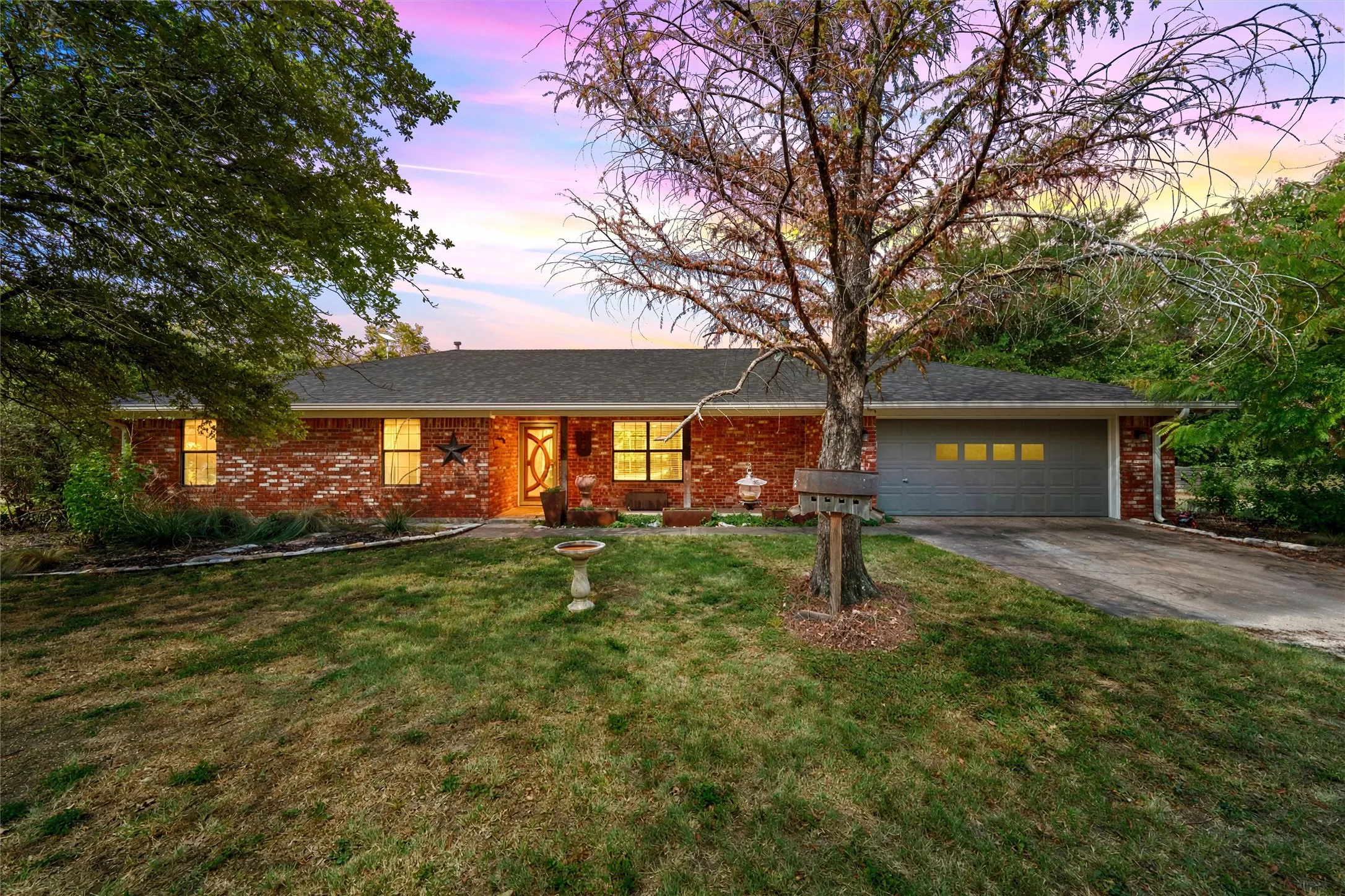 Brick exterior with a dark shingle roof, attached garage with panel windows, and a concrete driveway