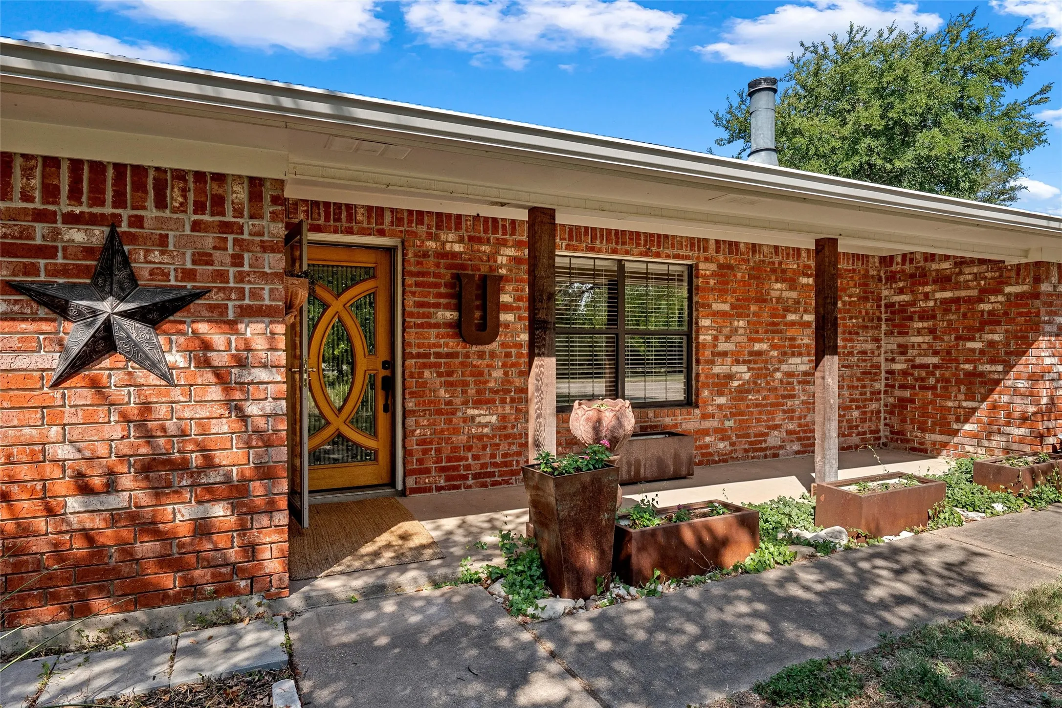 Brick exterior with covered front porch, decorative wood entry door, and dark-framed window