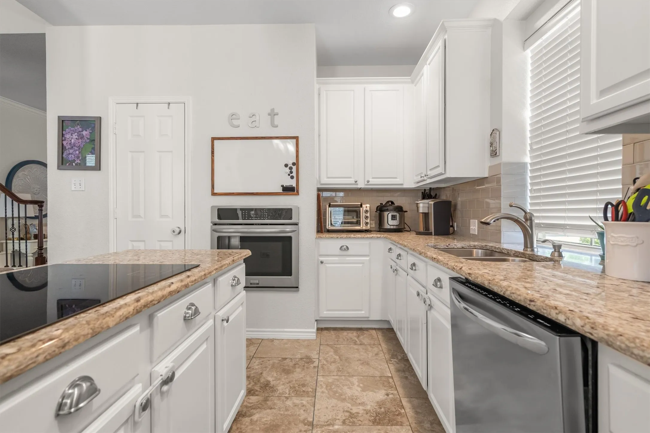 Kitchen featuring white cabinetry, granite countertops, stainless steel appliances, a built-in oven, and tile flooring