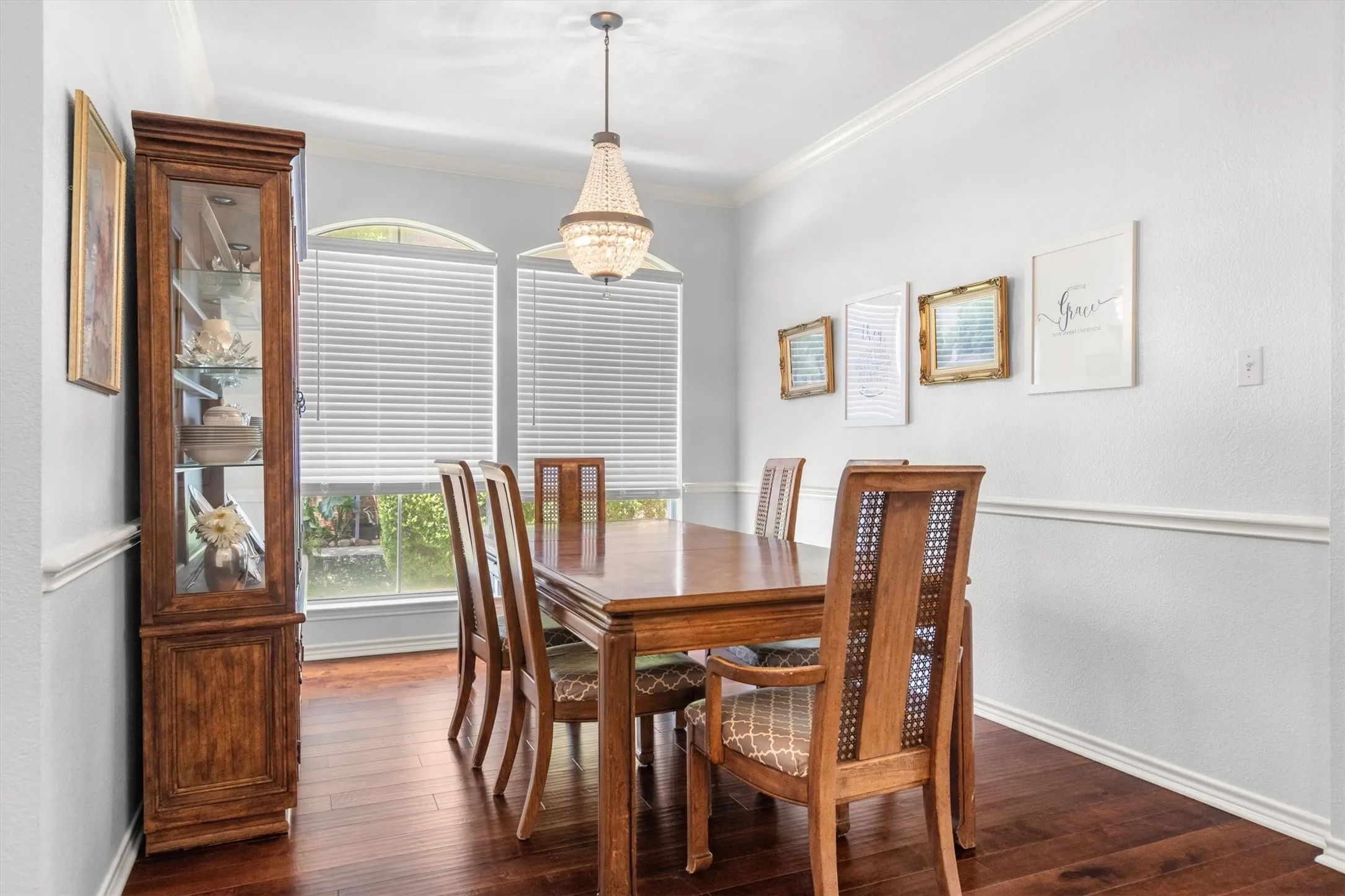 Wood-finish flooring, white walls with chair rail molding, and a beaded chandelier