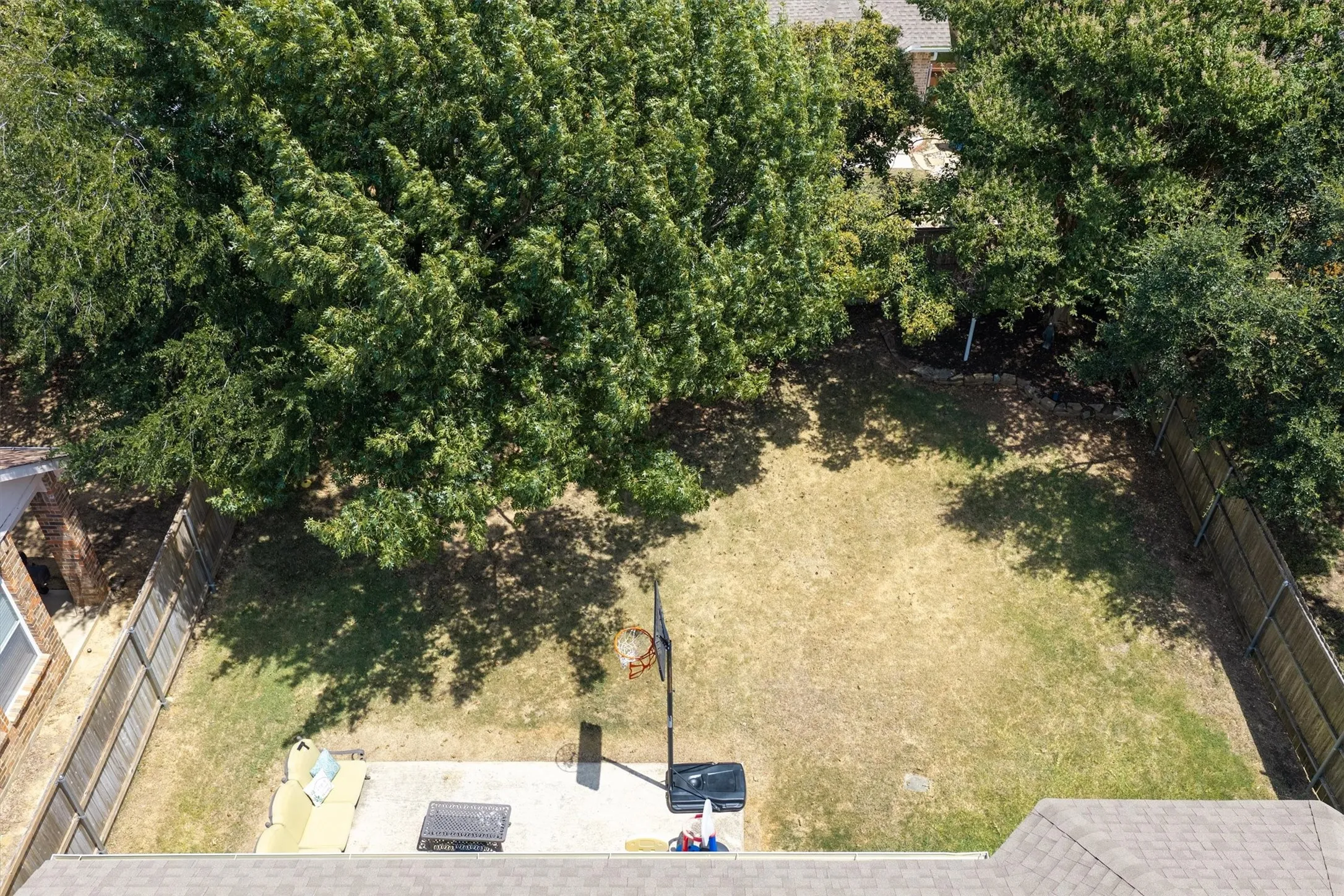 Expansive backyard featuring a large grass area, mature trees, a privacy fence, and a paved patio