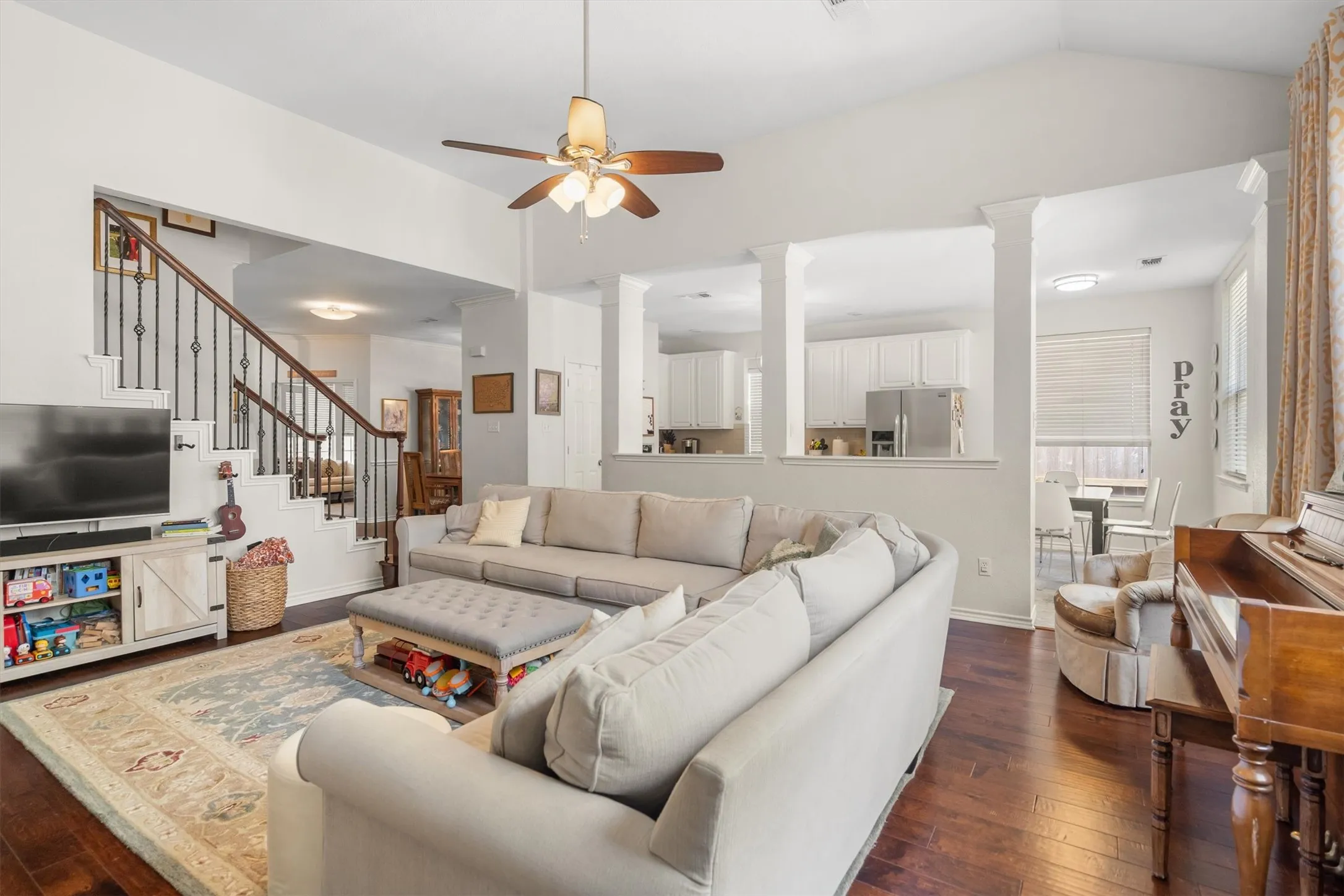 Open-concept living space with dark wood-finish flooring, a vaulted ceiling, and an overhead ceiling fan