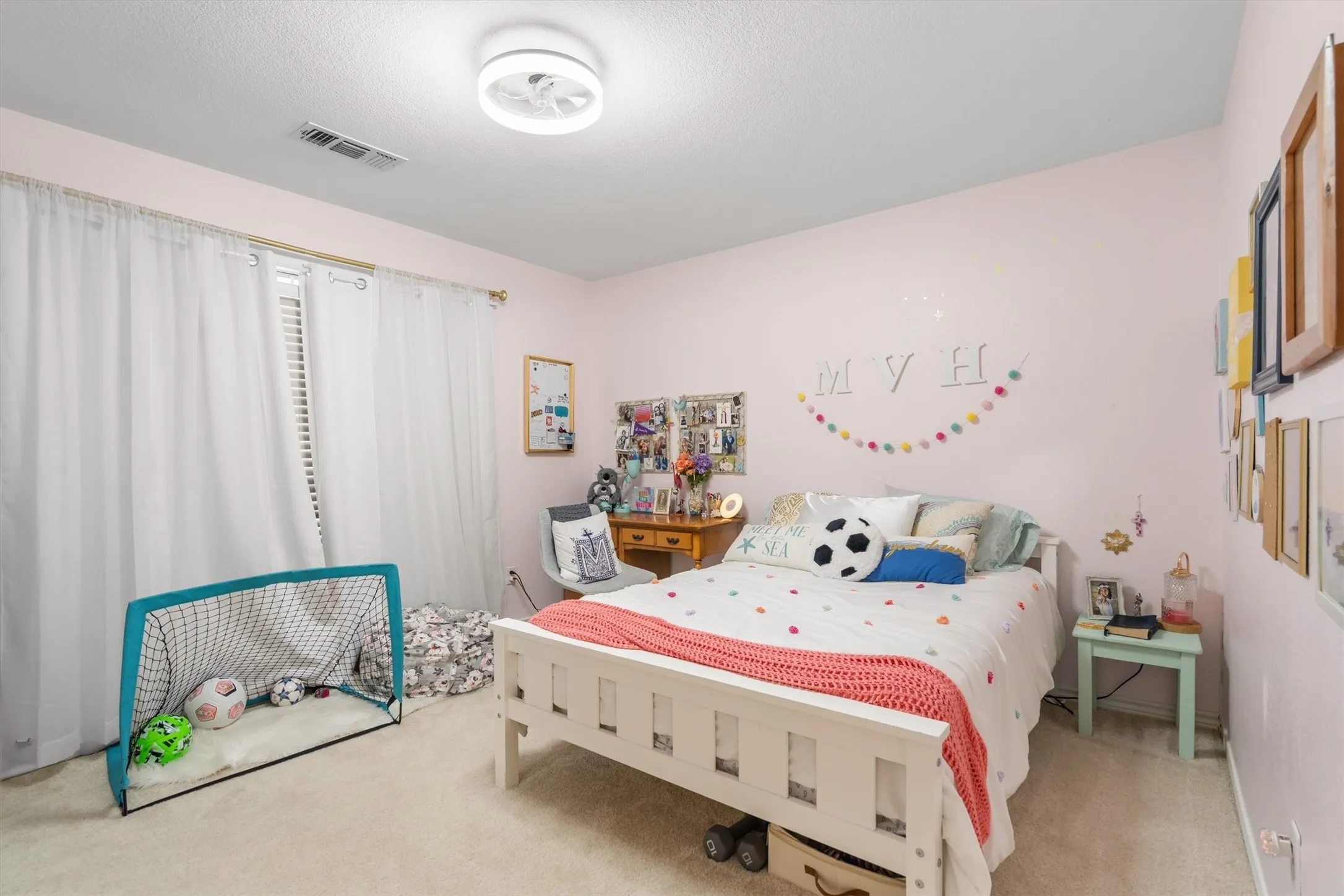Carpeted room with a ceiling-mounted light fixture, window with blinds and sheer drapes, and painted walls