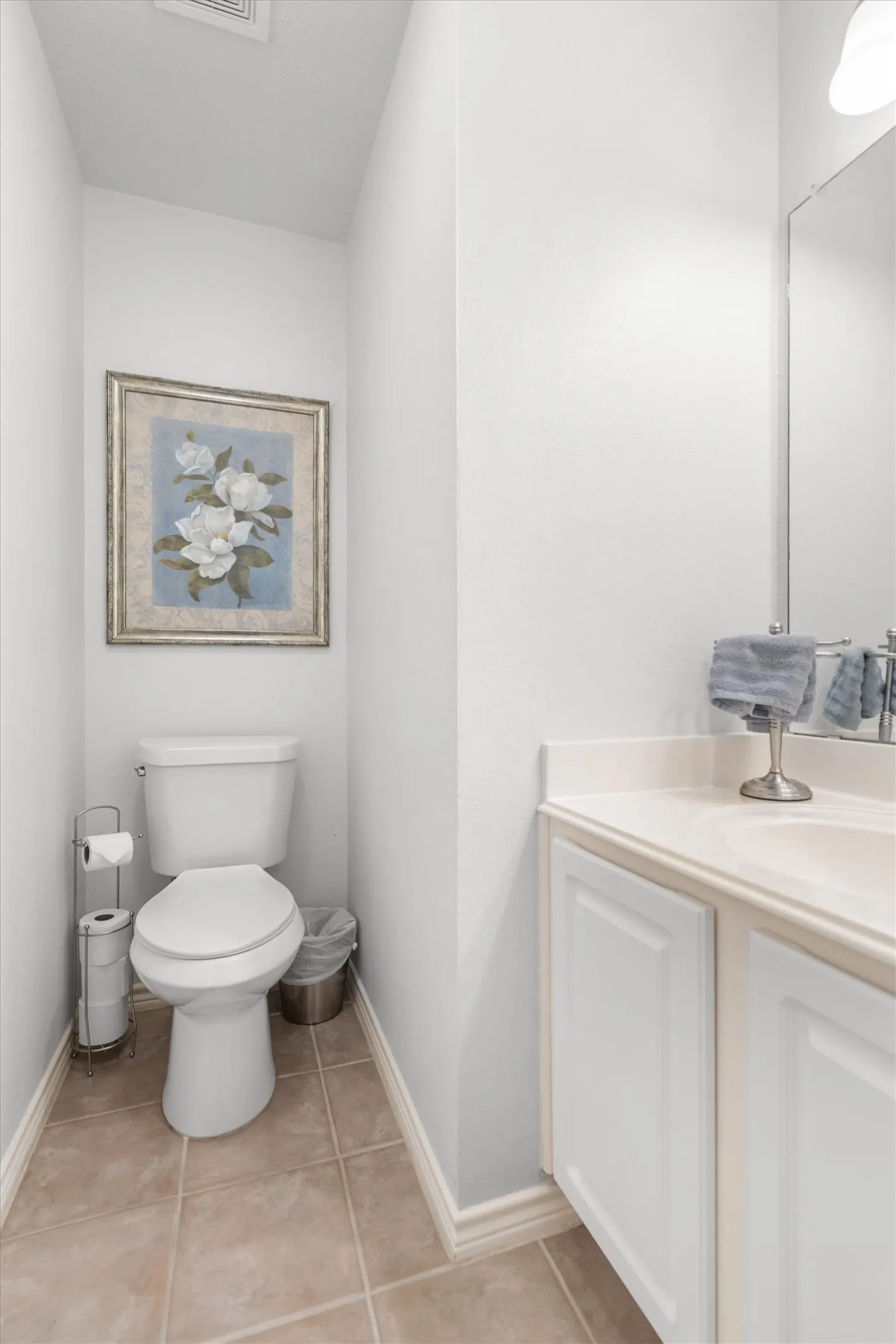 White vanity with panel-front cabinetry, an integrated sink, and a light-toned countertop