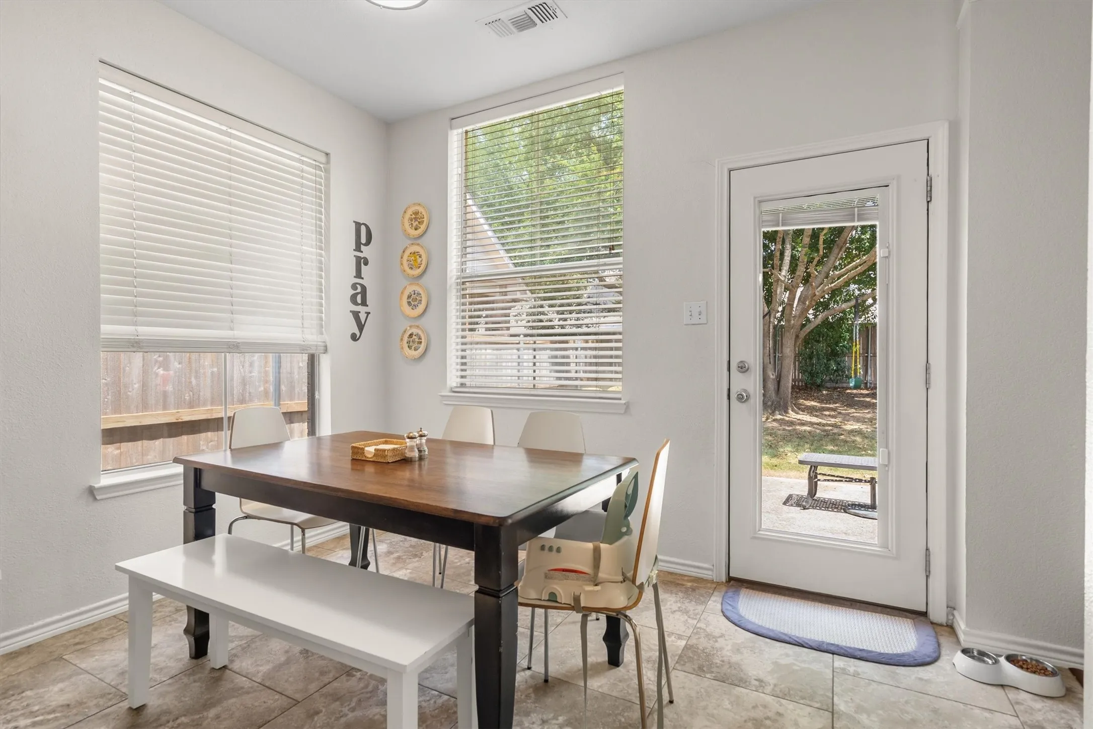 Light-filled interior with multiple windows, glass-paneled exterior door, and neutral tile flooring
