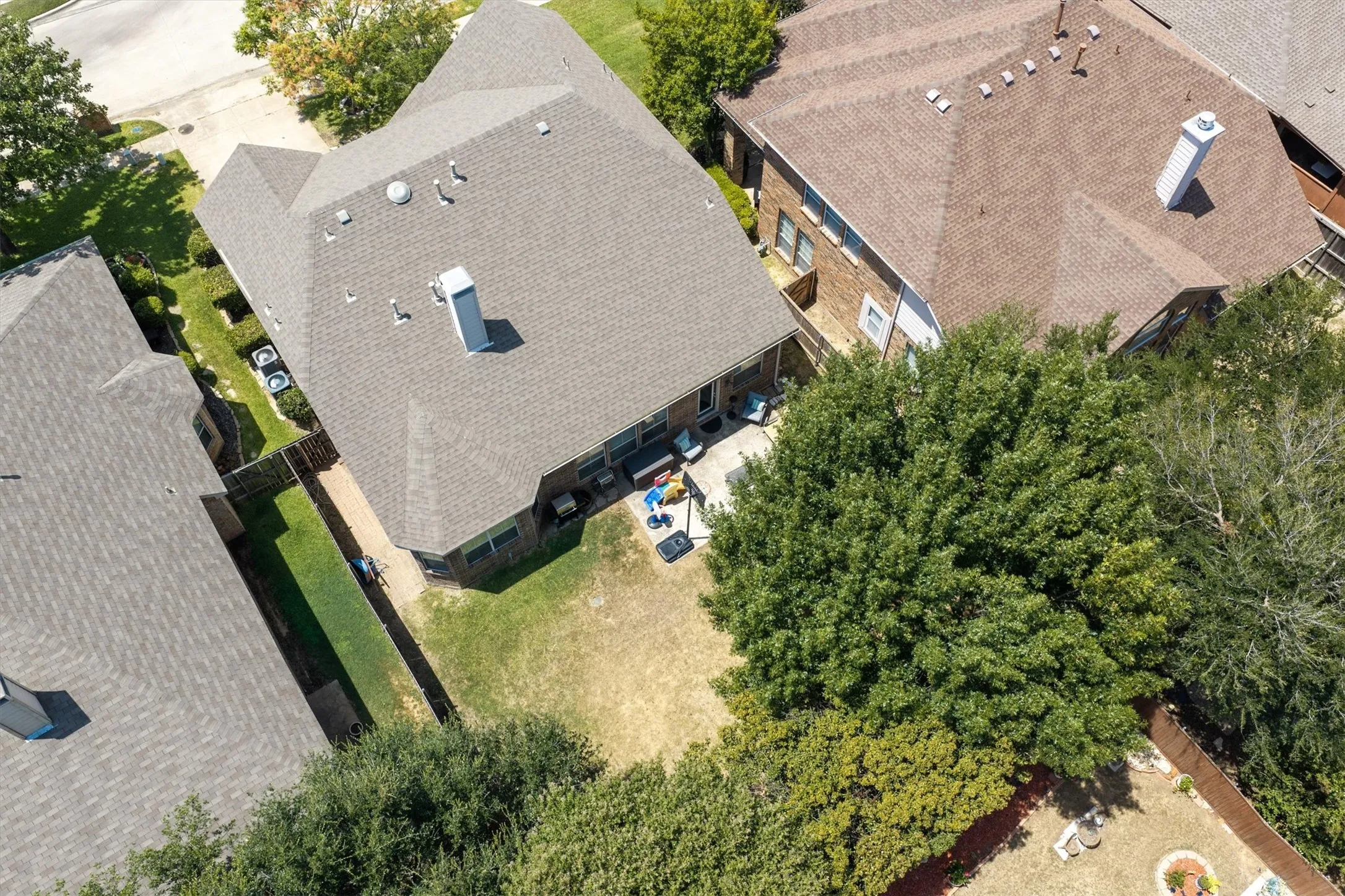 Expansive rear yard featuring mature trees and a paved patio area