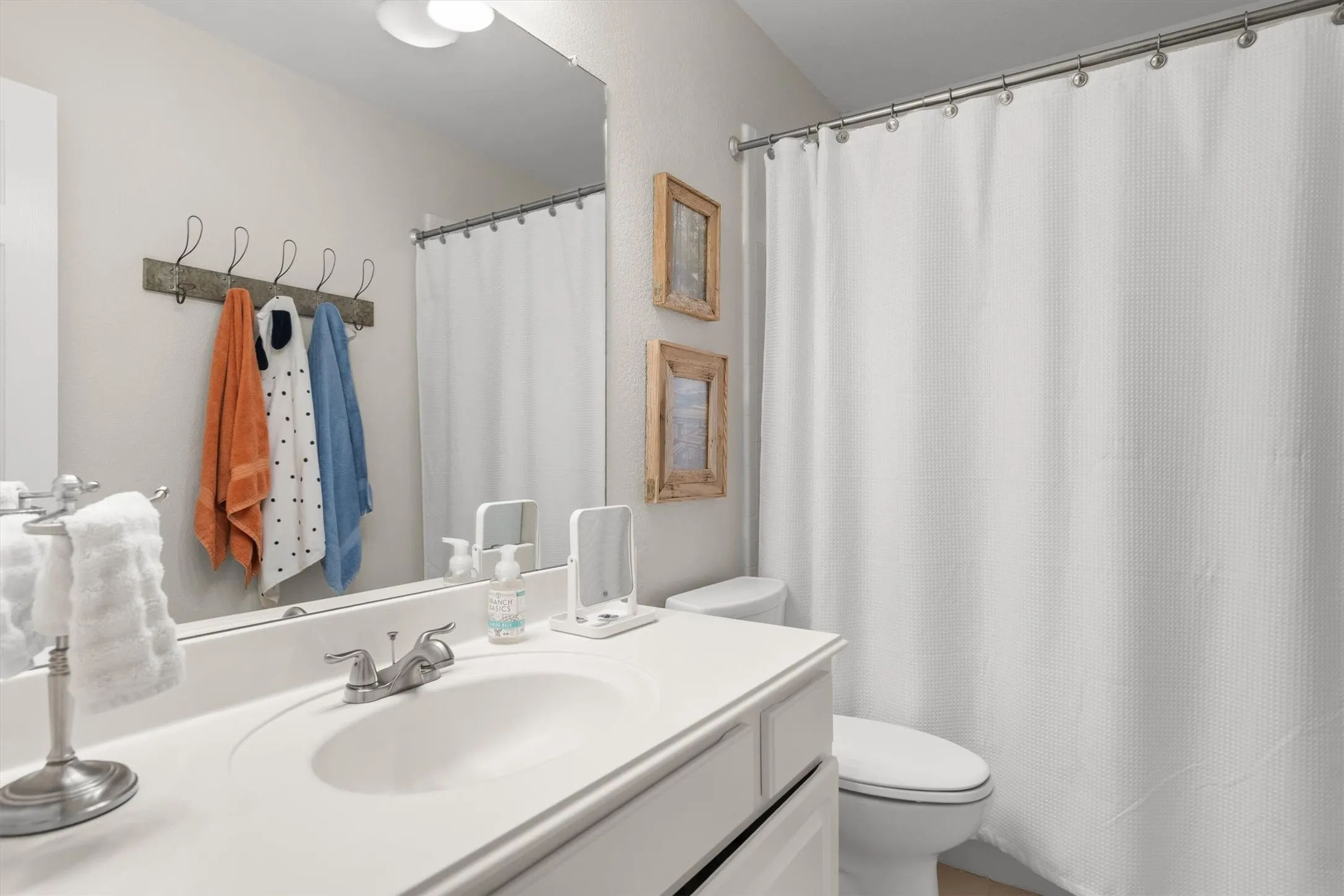 White vanity with integrated sink, chrome-finish faucet, and full-width mirror