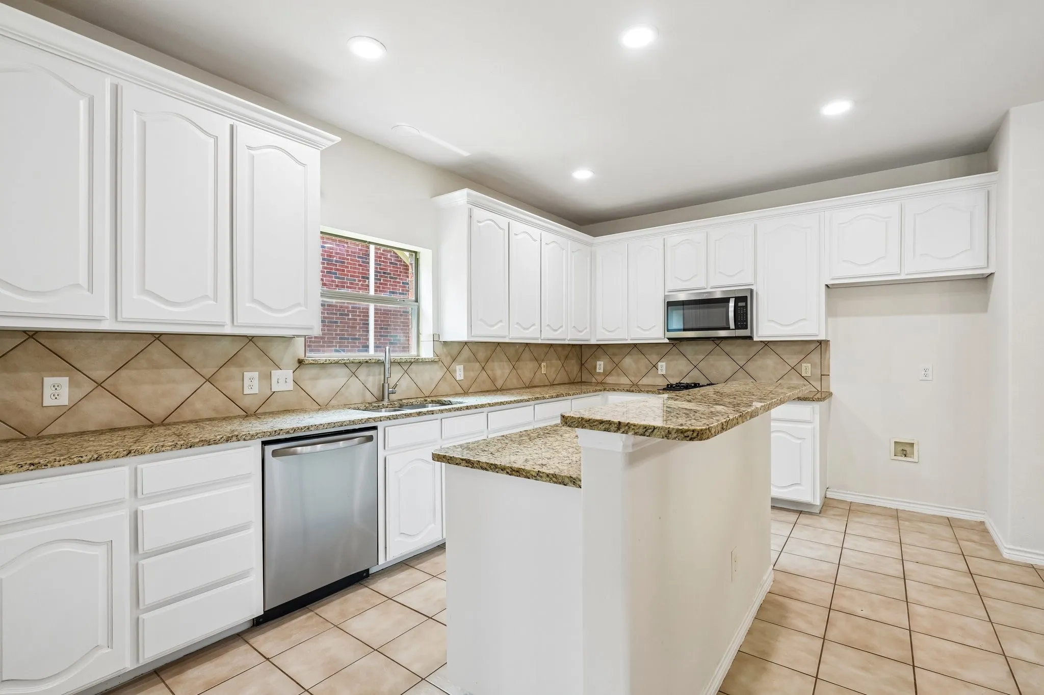 Bright, spacious kitchen featuring crisp white cabinetry, granite countertops, stainless-steel appliances, ample storage.