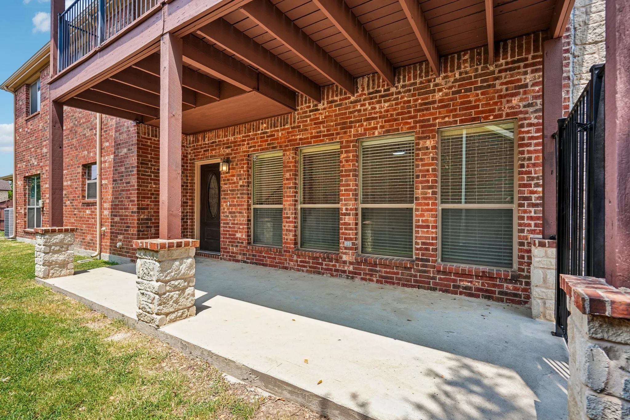 Inviting covered entryway featuring a spacious patio area, classic brick exterior, and convenient access to the nice sized side yard