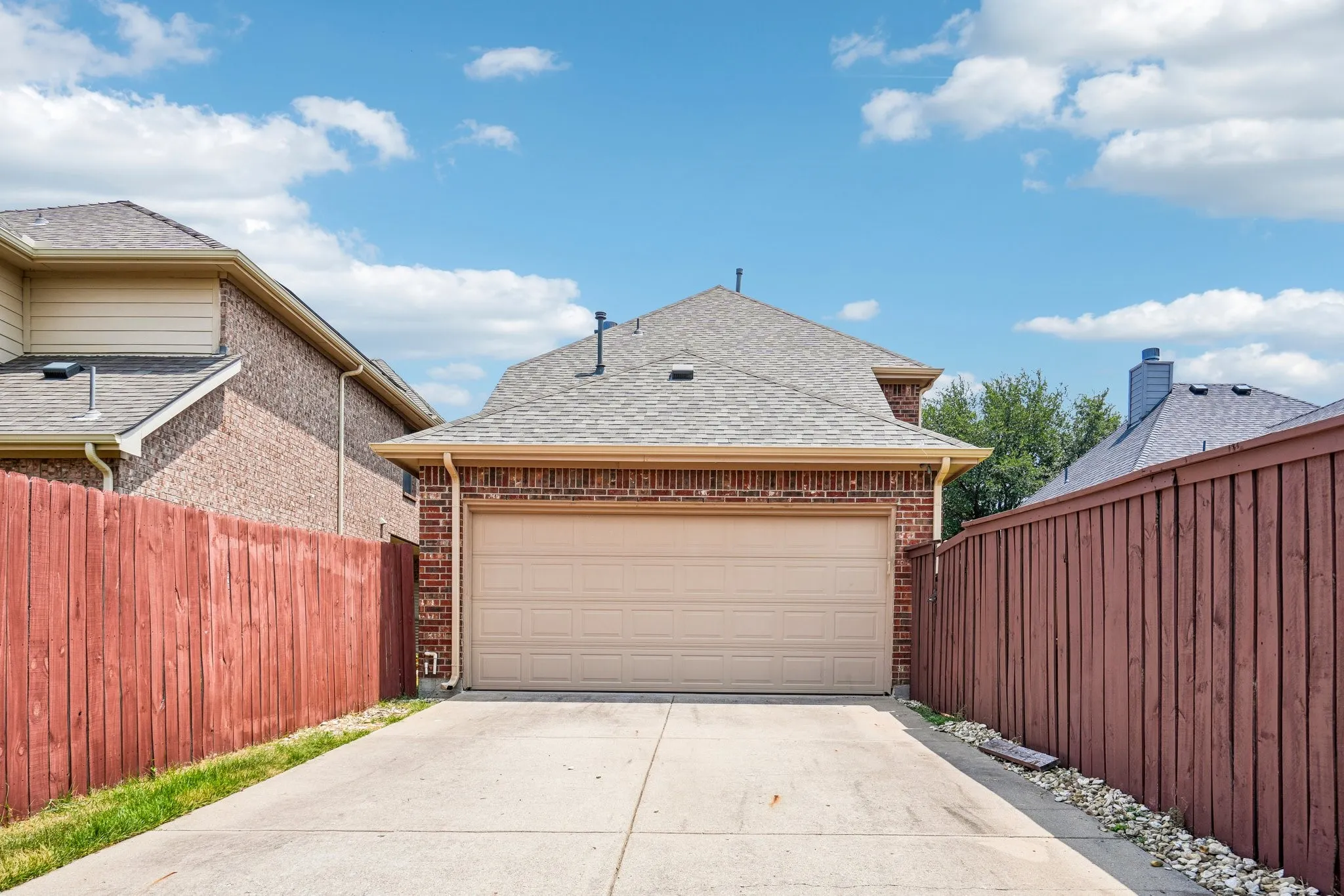 Private rear-entry two-car garage with a spacious driveway and fully fenced surroundings for added privacy.