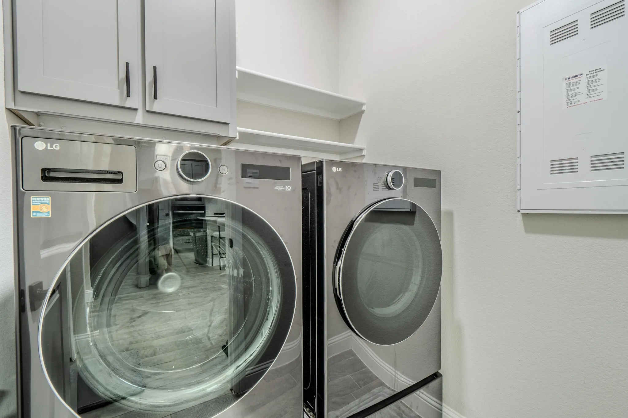 Laundry area featuring gray cabinetry, integrated shelving, and wood-finish flooring