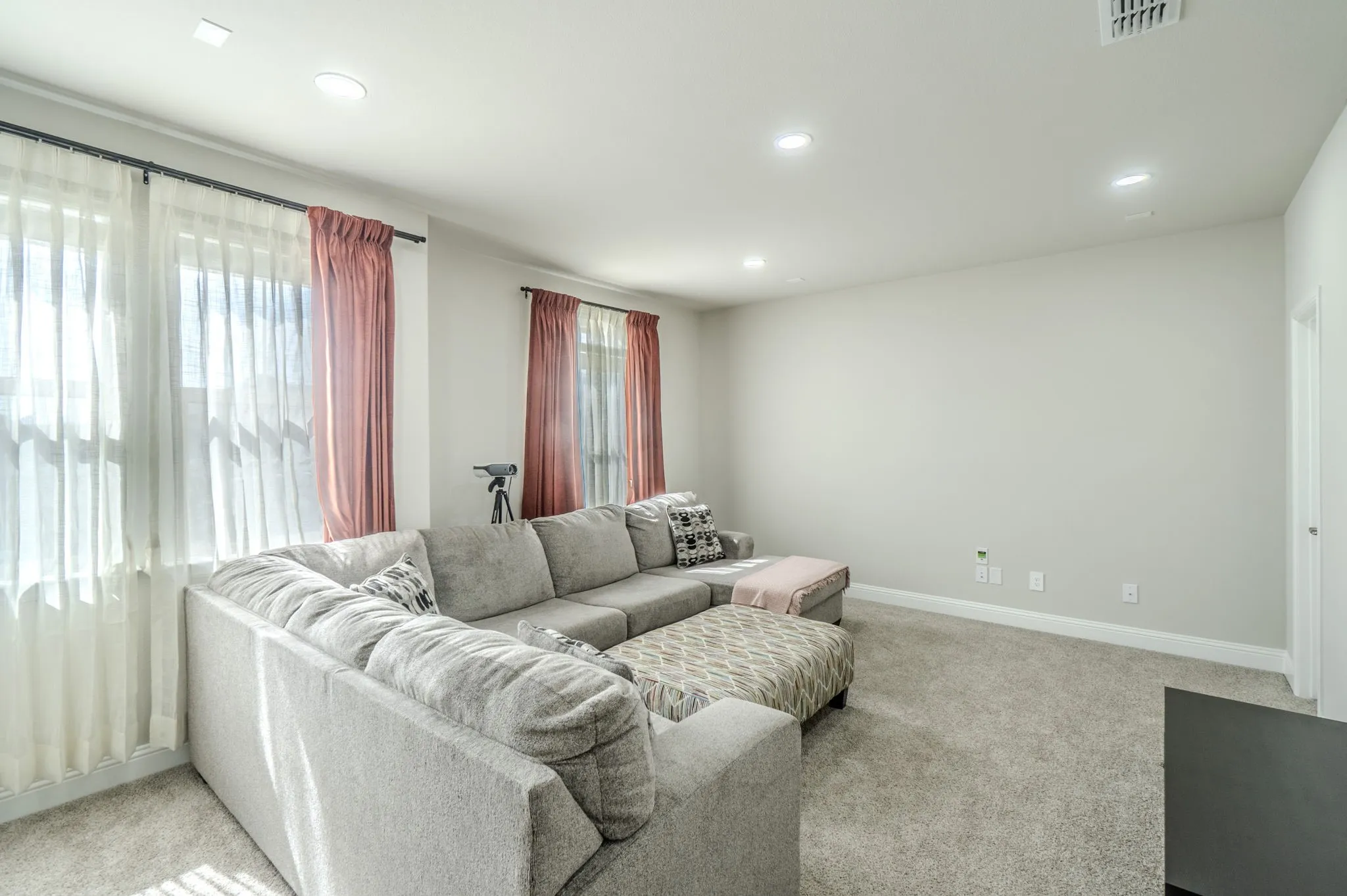 Recessed lighting, light gray wall paint, white trim, and light-colored carpeting