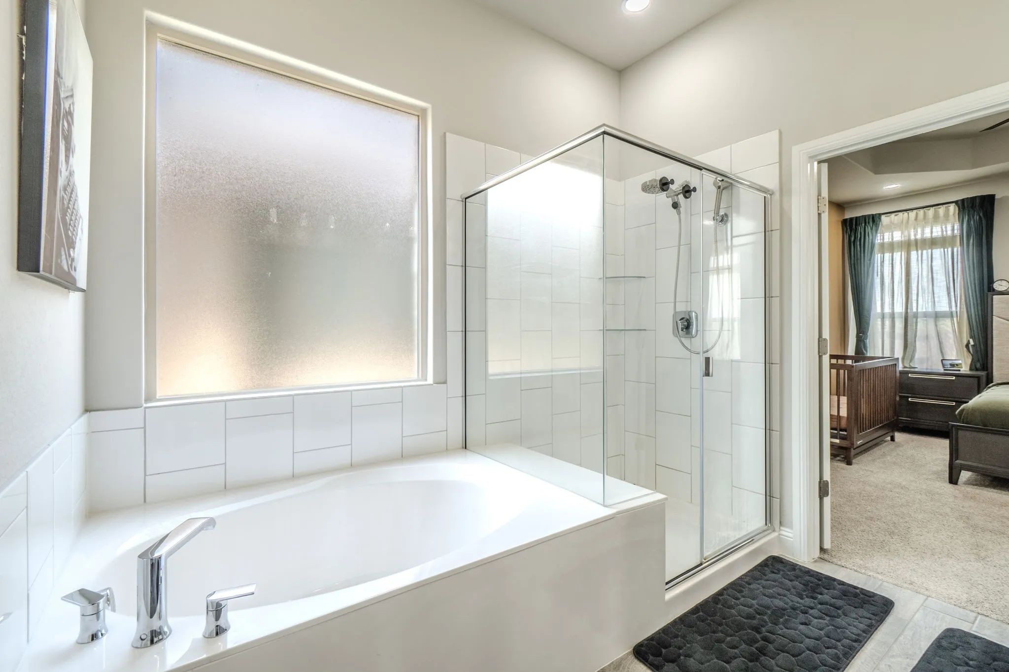 Soaking tub with chrome fixtures, enclosed glass shower, frosted privacy window, and recessed lighting