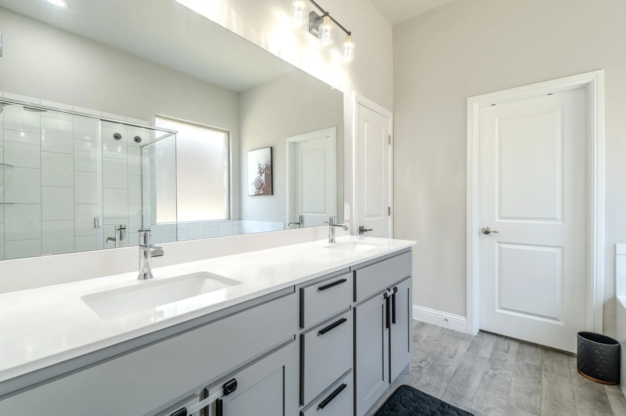 Dual vanity with integrated sinks, light gray cabinetry, and a full-width mirror