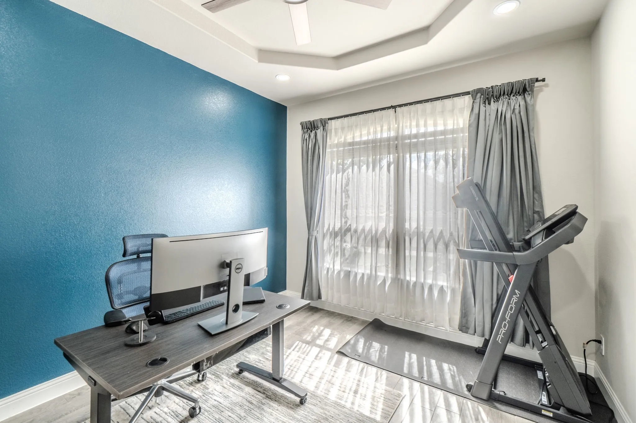 Recessed lighting, ceiling fan, tray ceiling, wood-finish flooring, and large window