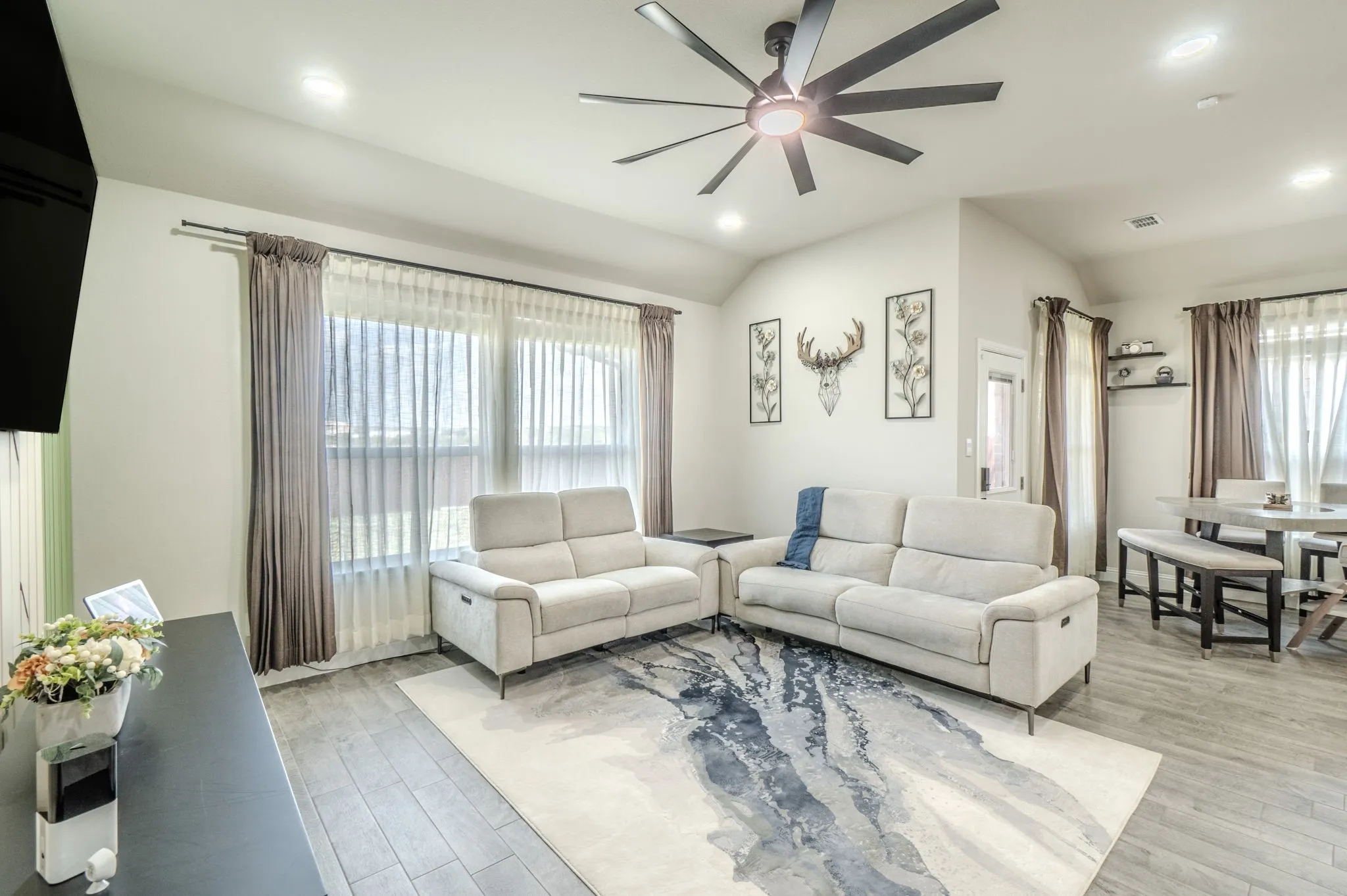 Vaulted ceiling with a contemporary ceiling fan, recessed lighting, wood-finish flooring, and expansive windows