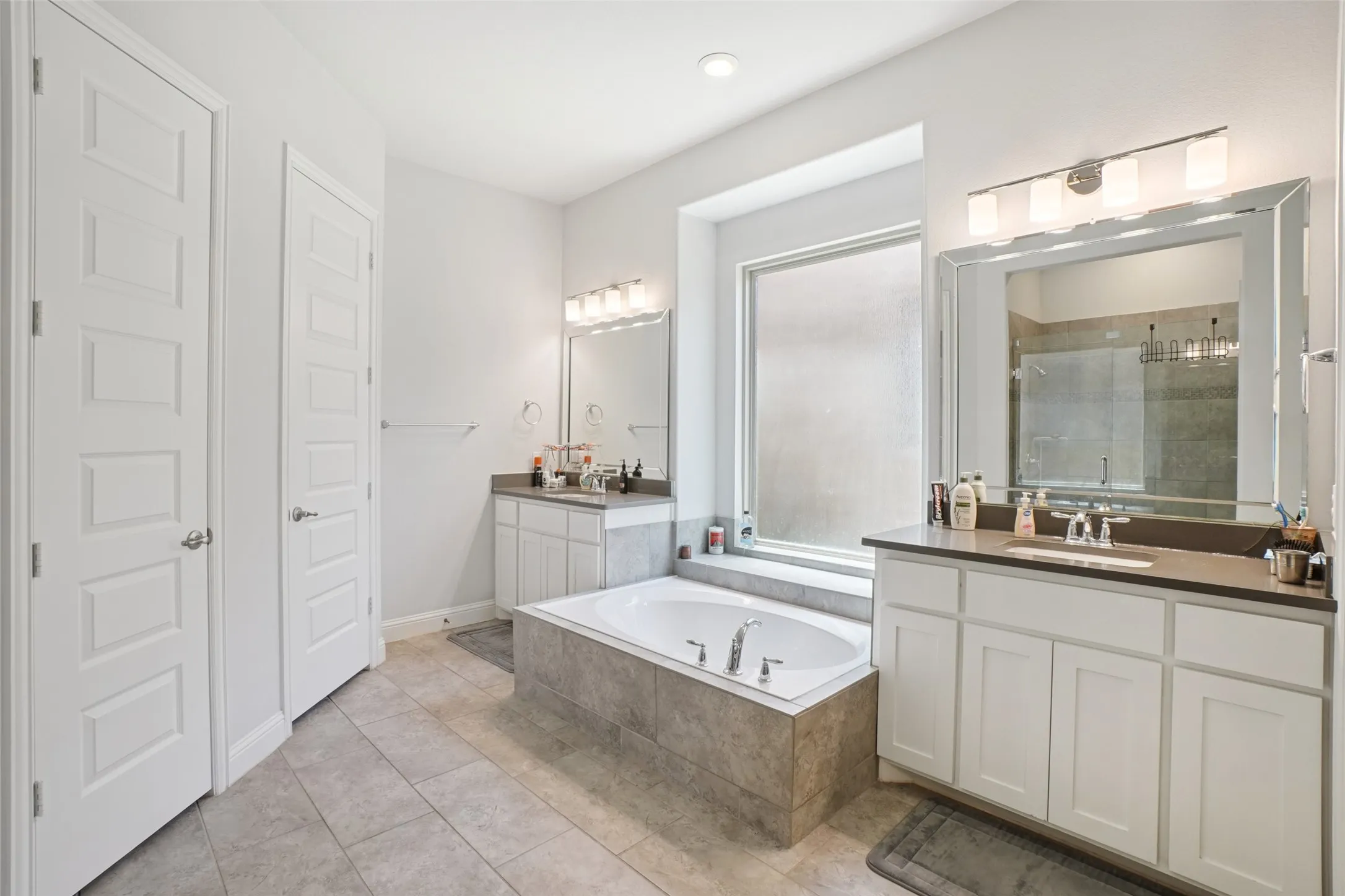 Full bathroom featuring a stall shower, two vanities, a bath, and tile patterned flooring
