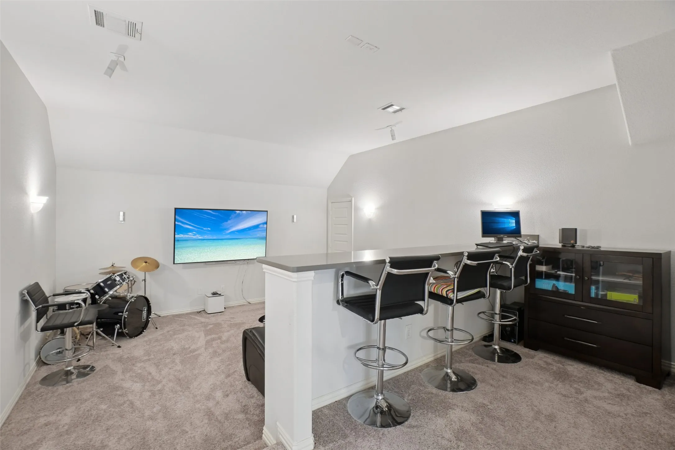 Home office with light carpet and vaulted ceiling