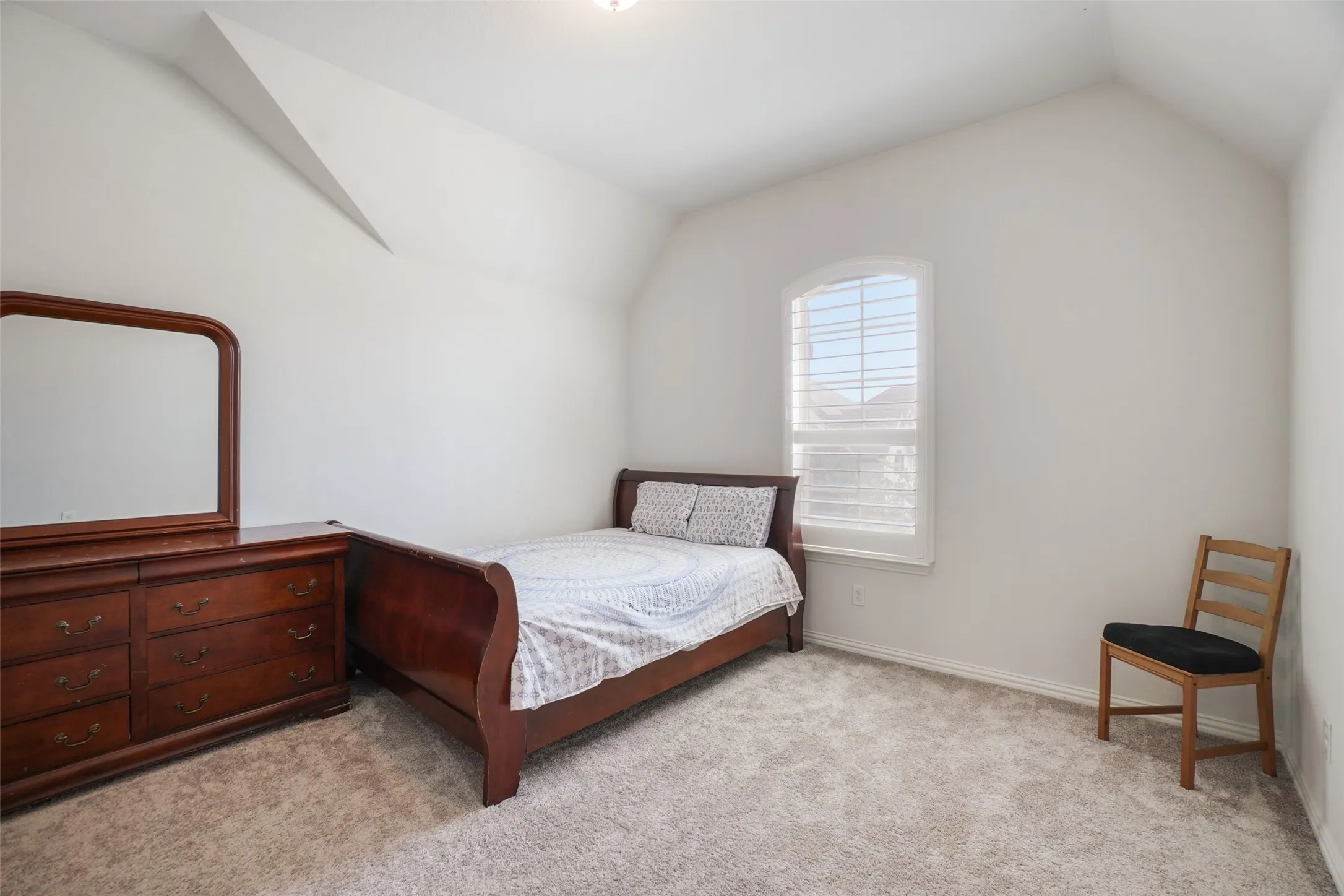Bedroom with vaulted ceiling and light colored carpet