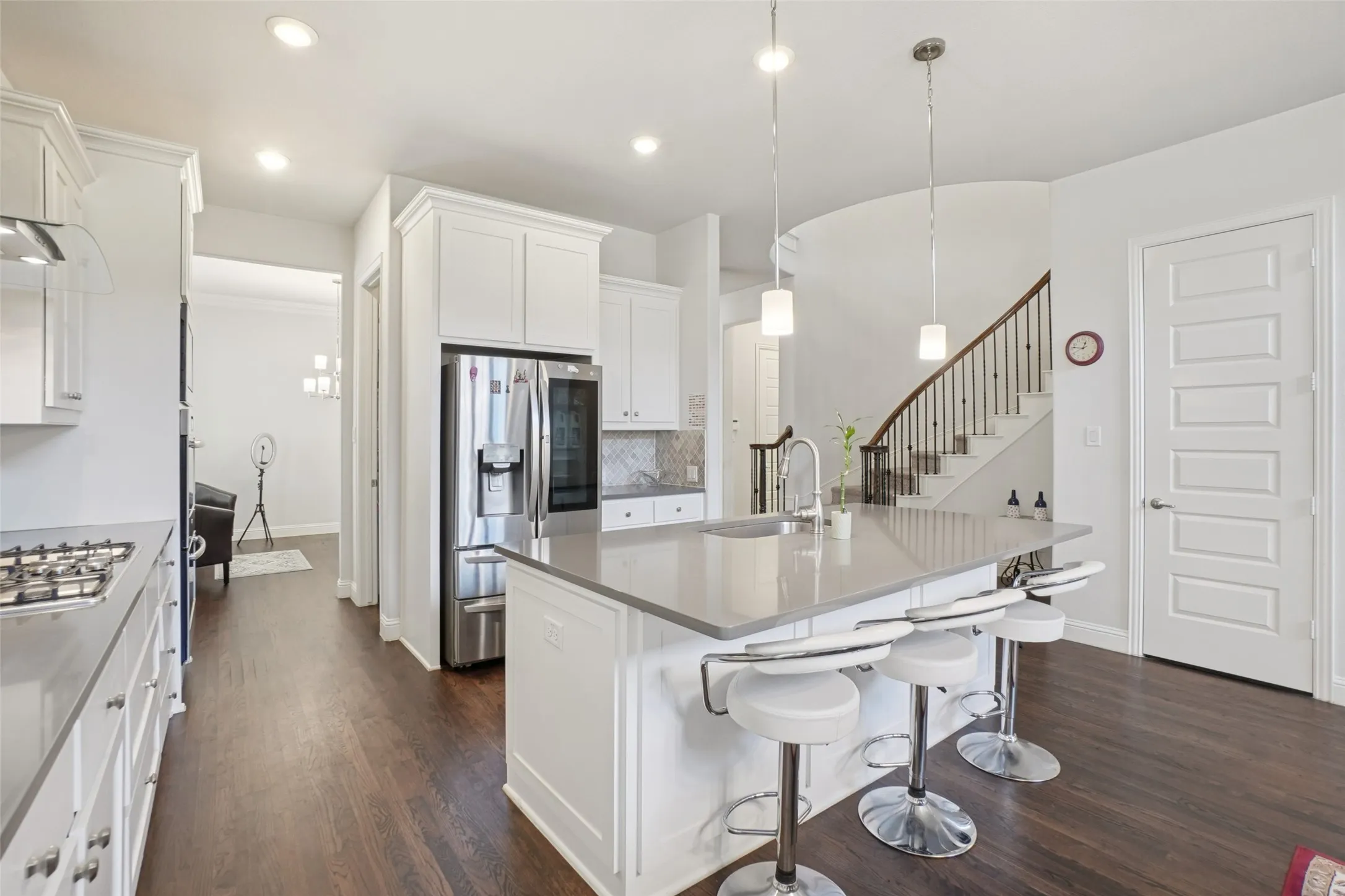 Kitchen featuring stainless steel appliances, dark wood finished floors, a center island with sink, white cabinets, and recessed lighting