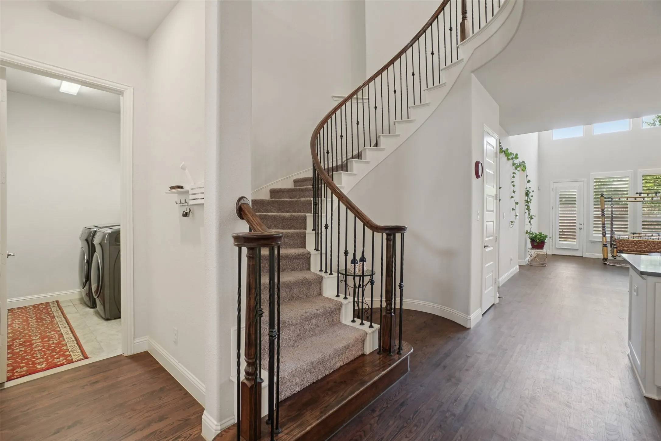 Stairway with separate washer and dryer, wood finished floors, and a towering ceiling
