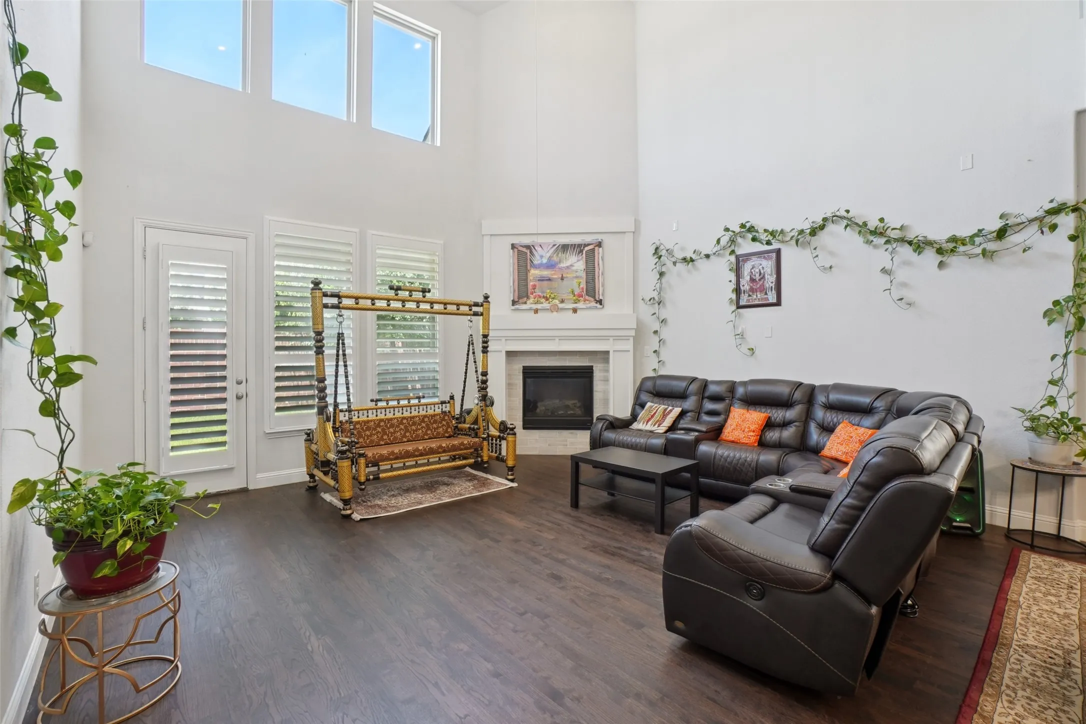Living room featuring wood finished floors, a towering ceiling, and a fireplace