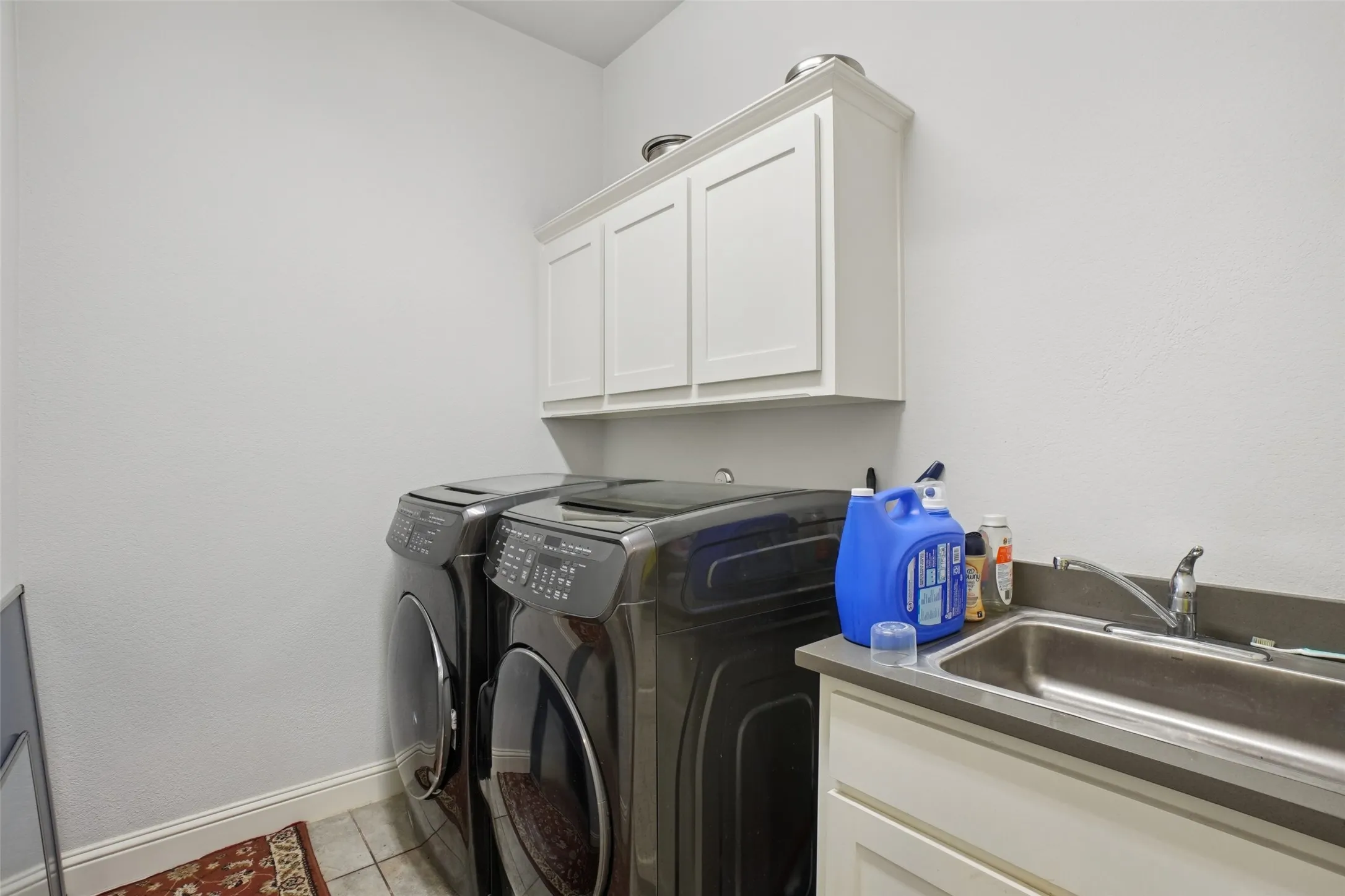 Laundry room with washing machine and dryer, cabinet space, and light tile patterned floors