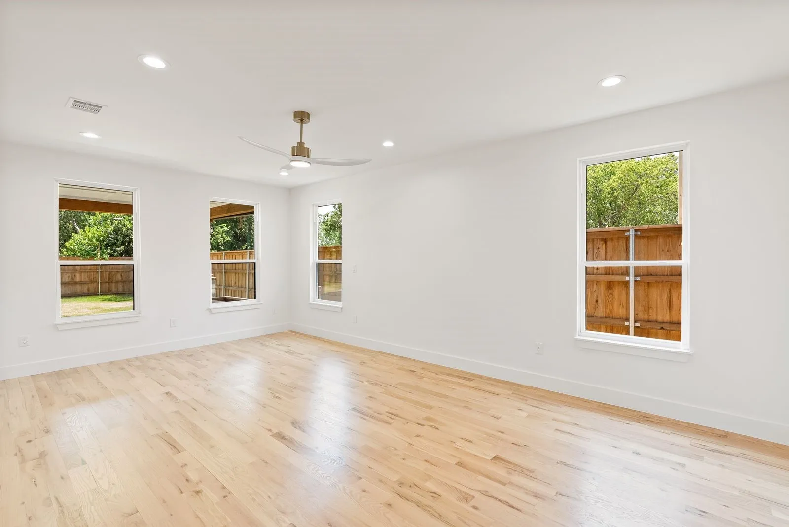 Light wood-finish flooring, recessed lighting, ceiling fan, multiple windows