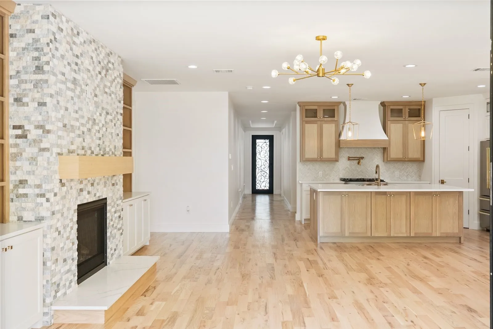 Hardwood flooring throughout, kitchen island with seating, built-in cabinetry, fireplace with tile surround, and recessed lighting