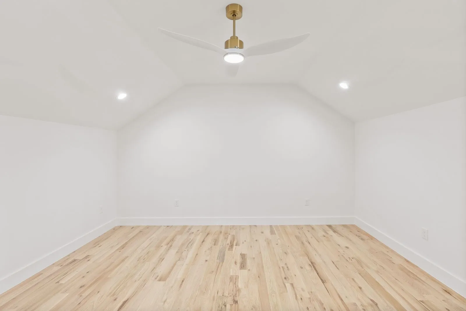 Vaulted ceiling with a contemporary gold-tone ceiling fan, recessed lighting, and light wood-finish flooring