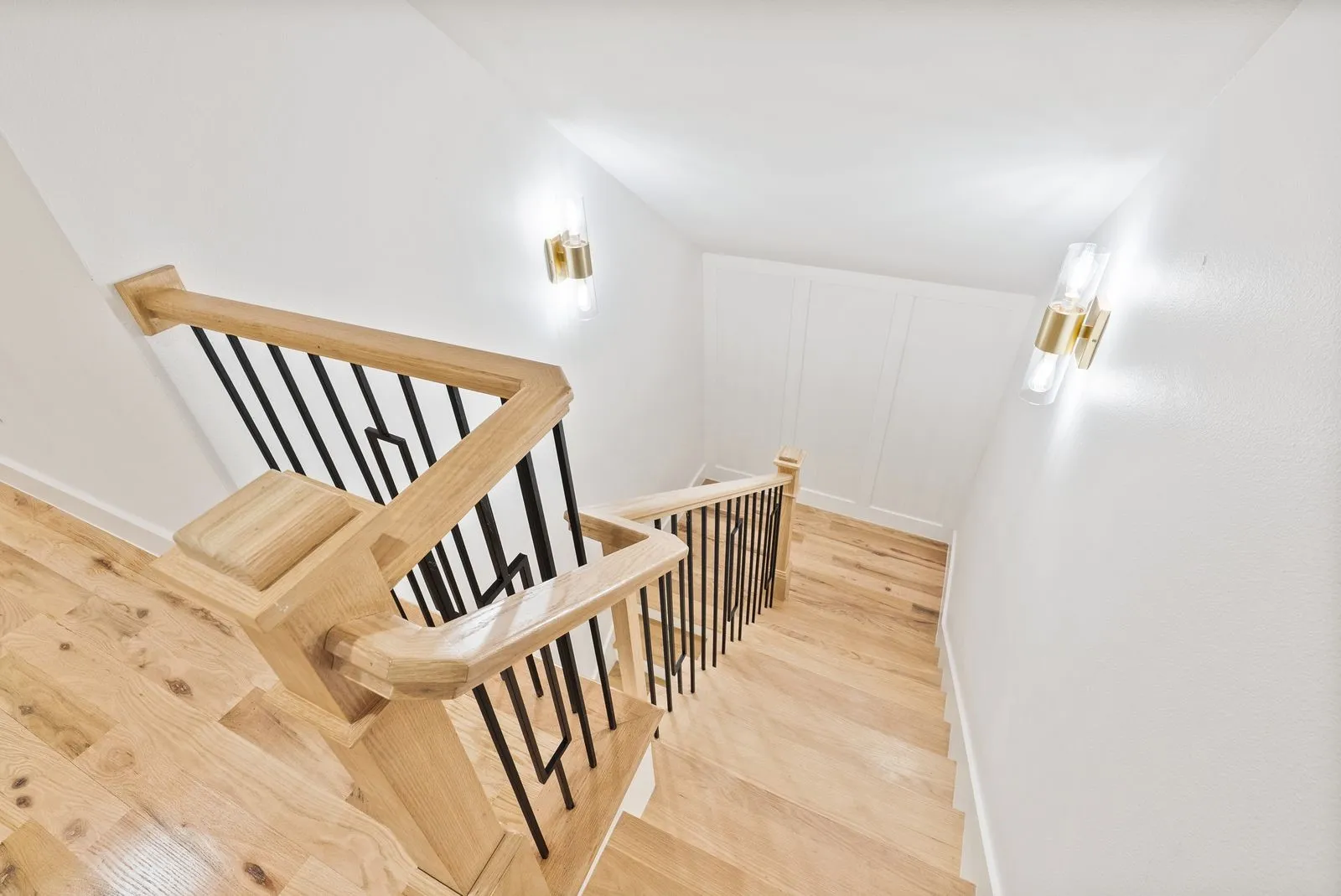 Hardwood staircase with natural wood-finish handrails and black metal balusters
