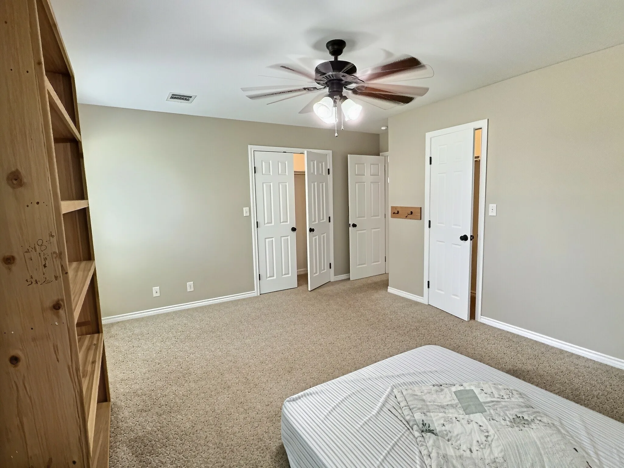 Neutral wall color, ceiling fan with integrated lighting, textured carpet flooring, white paneled doors