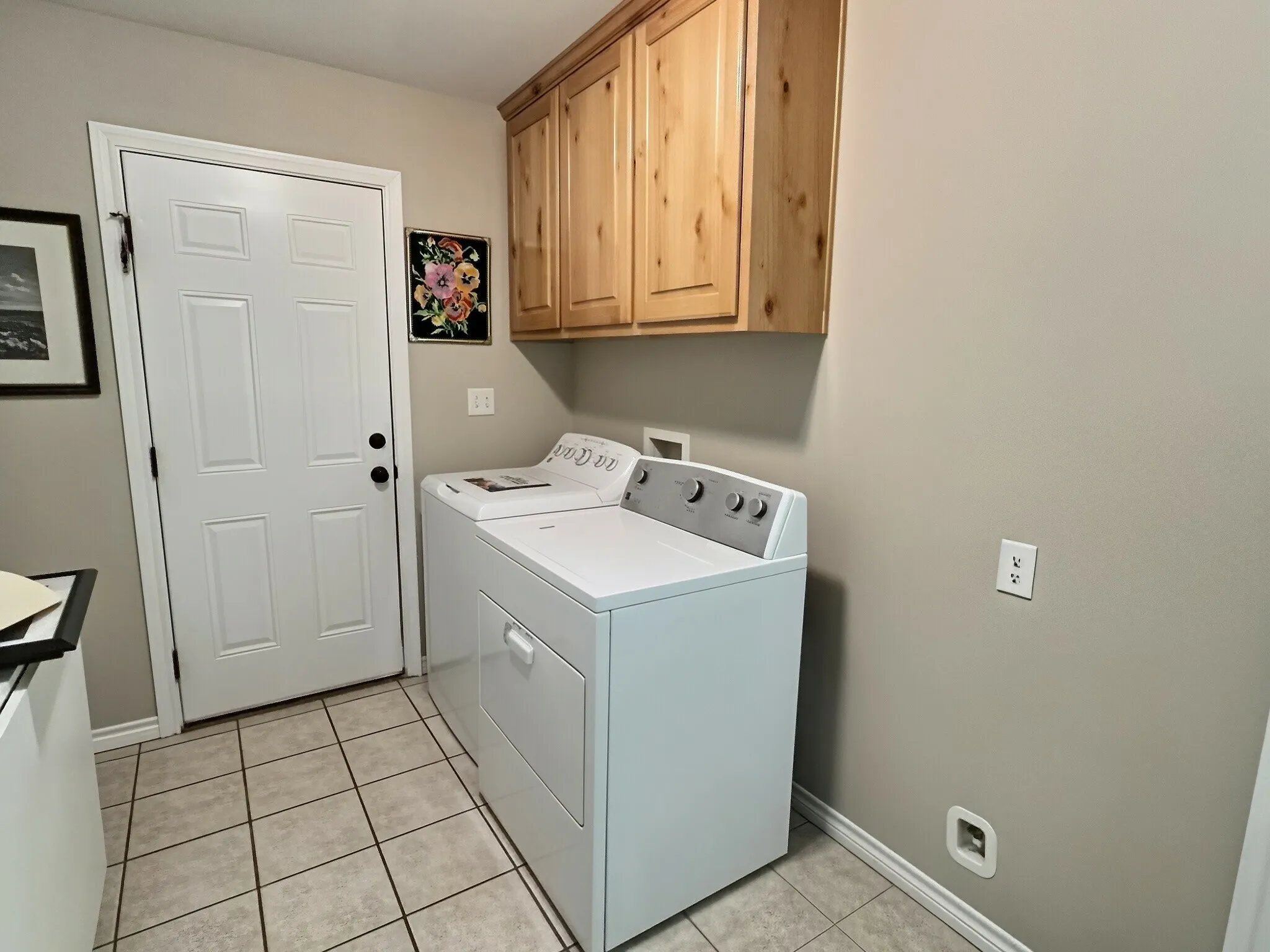 Utility area with tiled flooring, neutral wall color, and overhead wood cabinetry