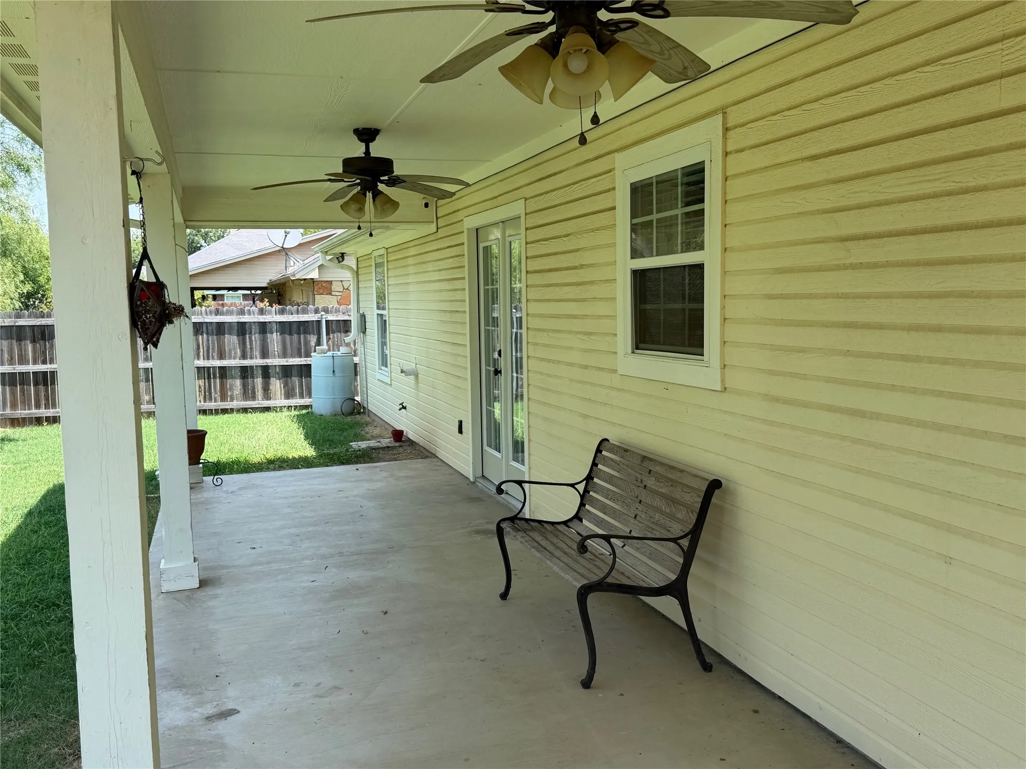 Covered patio with concrete flooring, dual ceiling fans, and siding exterior