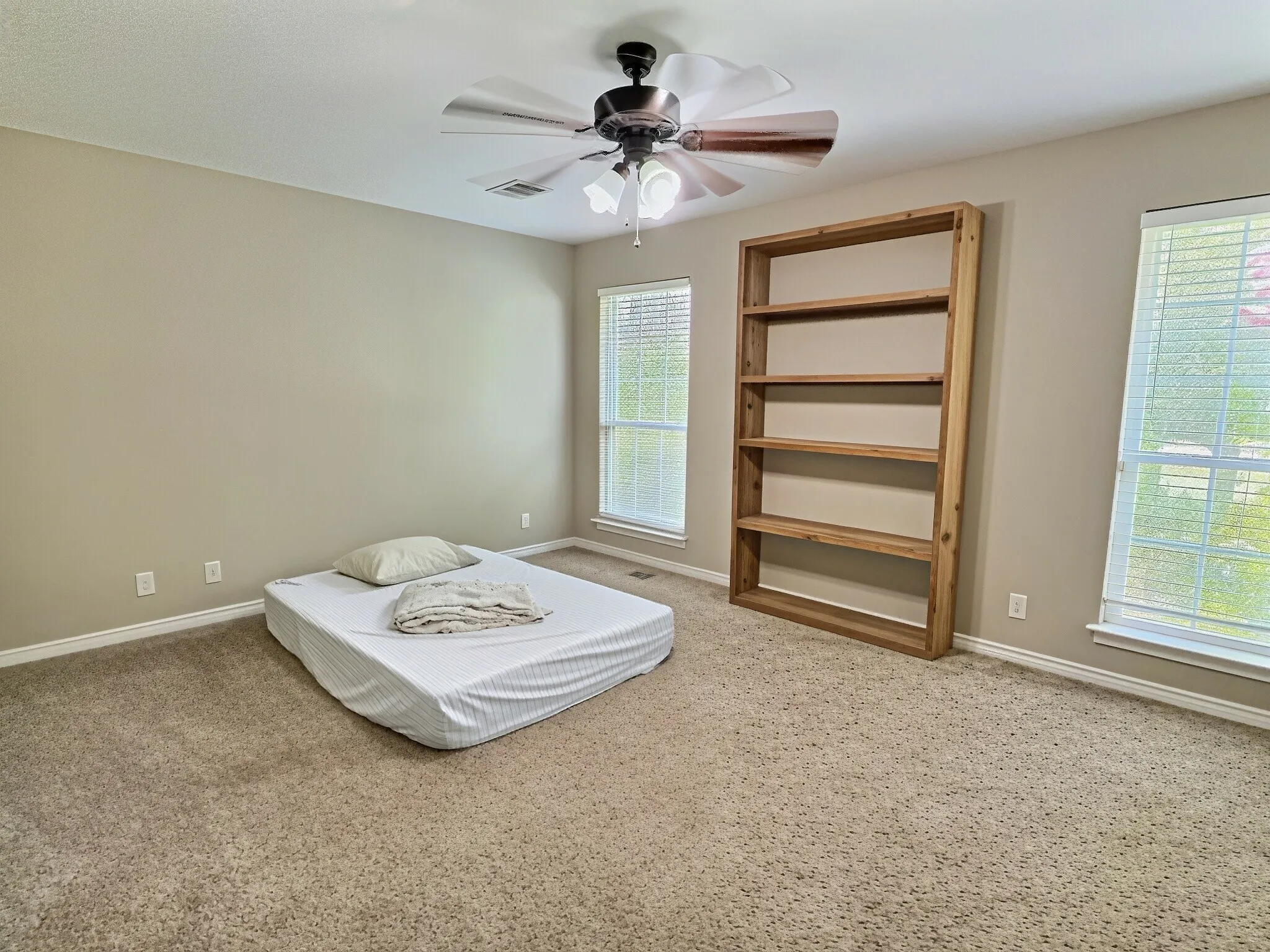 Neutral-toned walls, carpet flooring, and a ceiling fan with integrated lighting