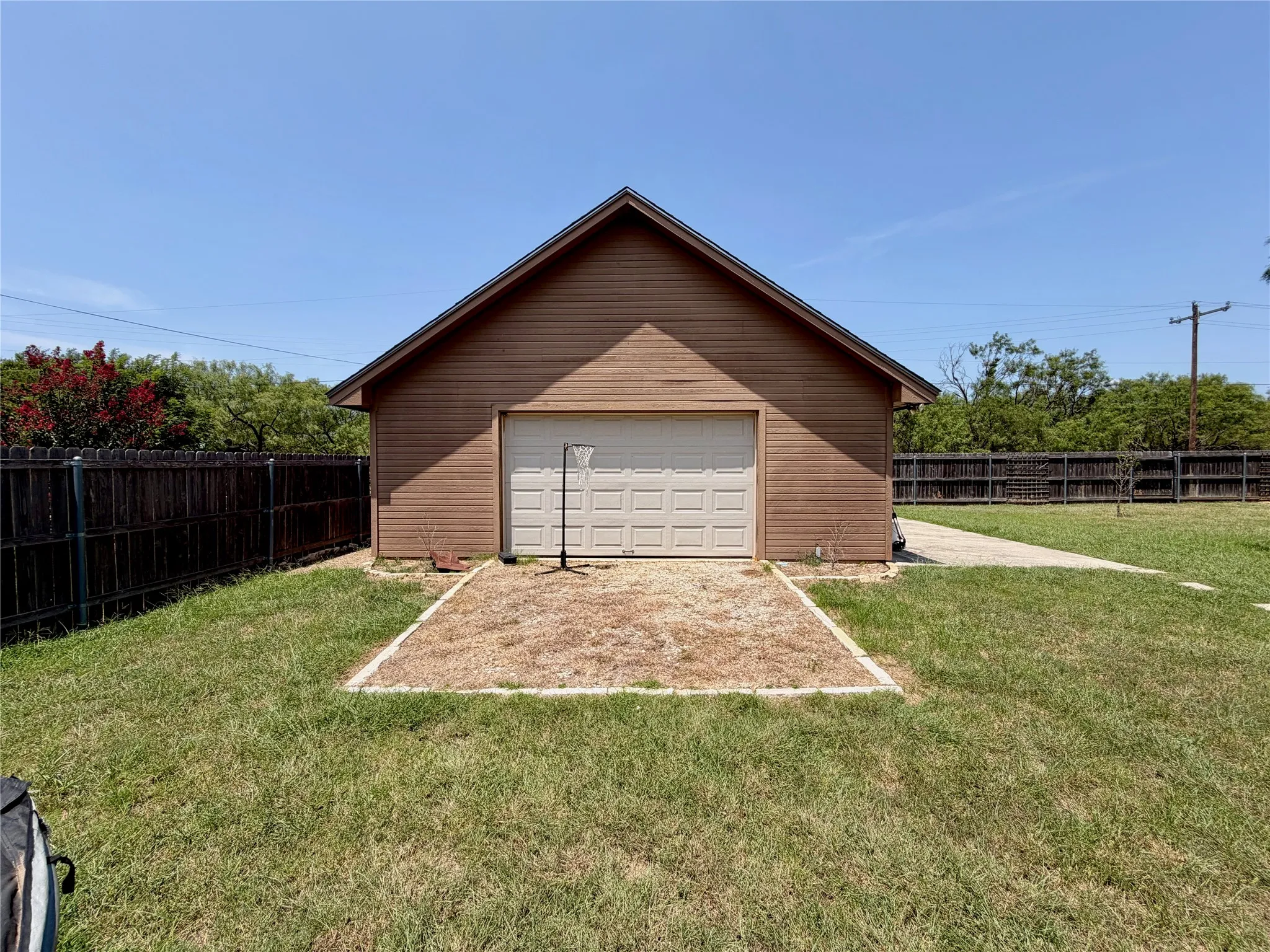 Detached garage with a paneled garage door, featuring wood-finish siding and a gabled roof