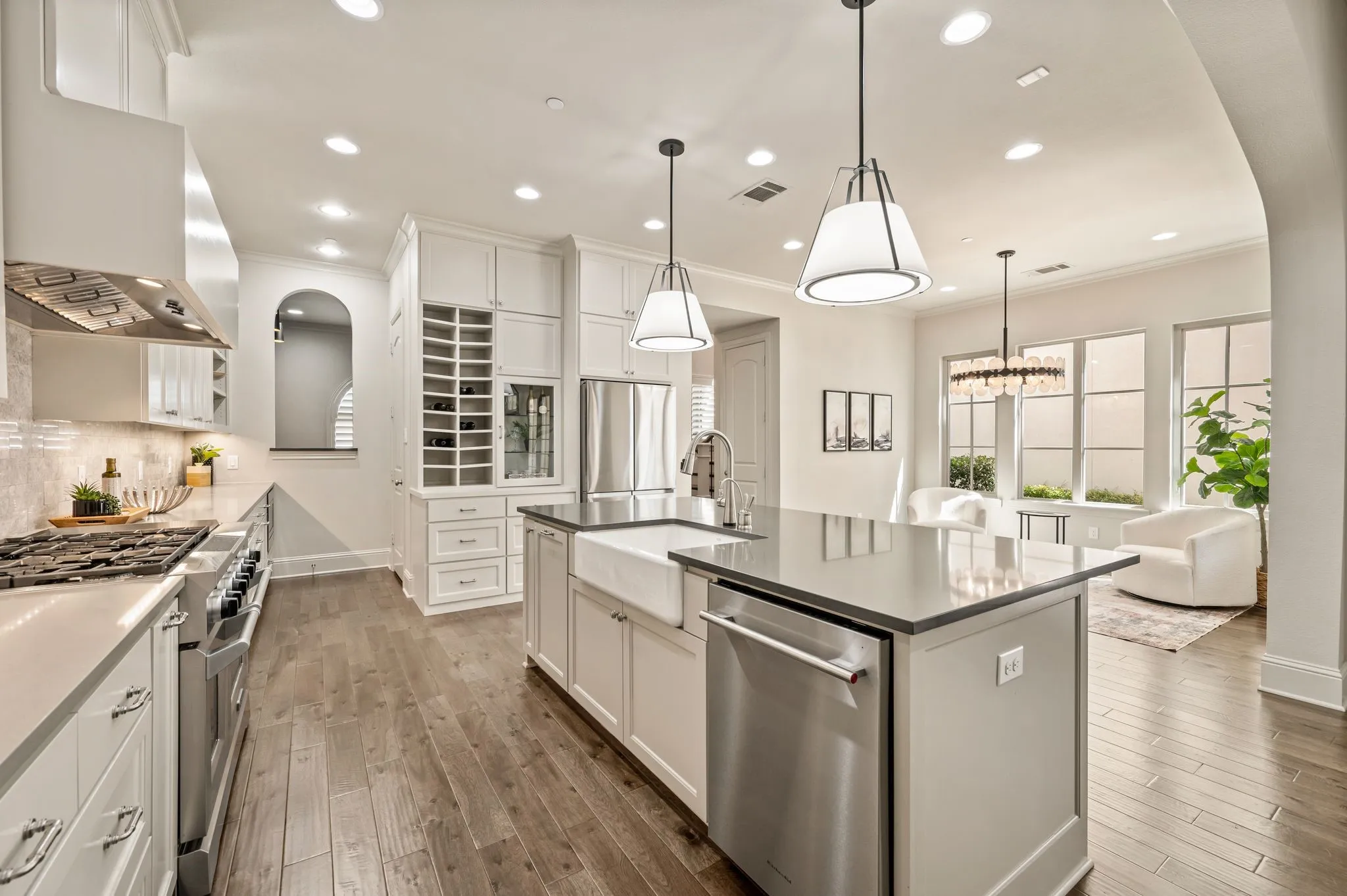 Gourmet kitchen featuring stainless steel appliances, a farmhouse sink, stone countertops, and extensive white cabinetry