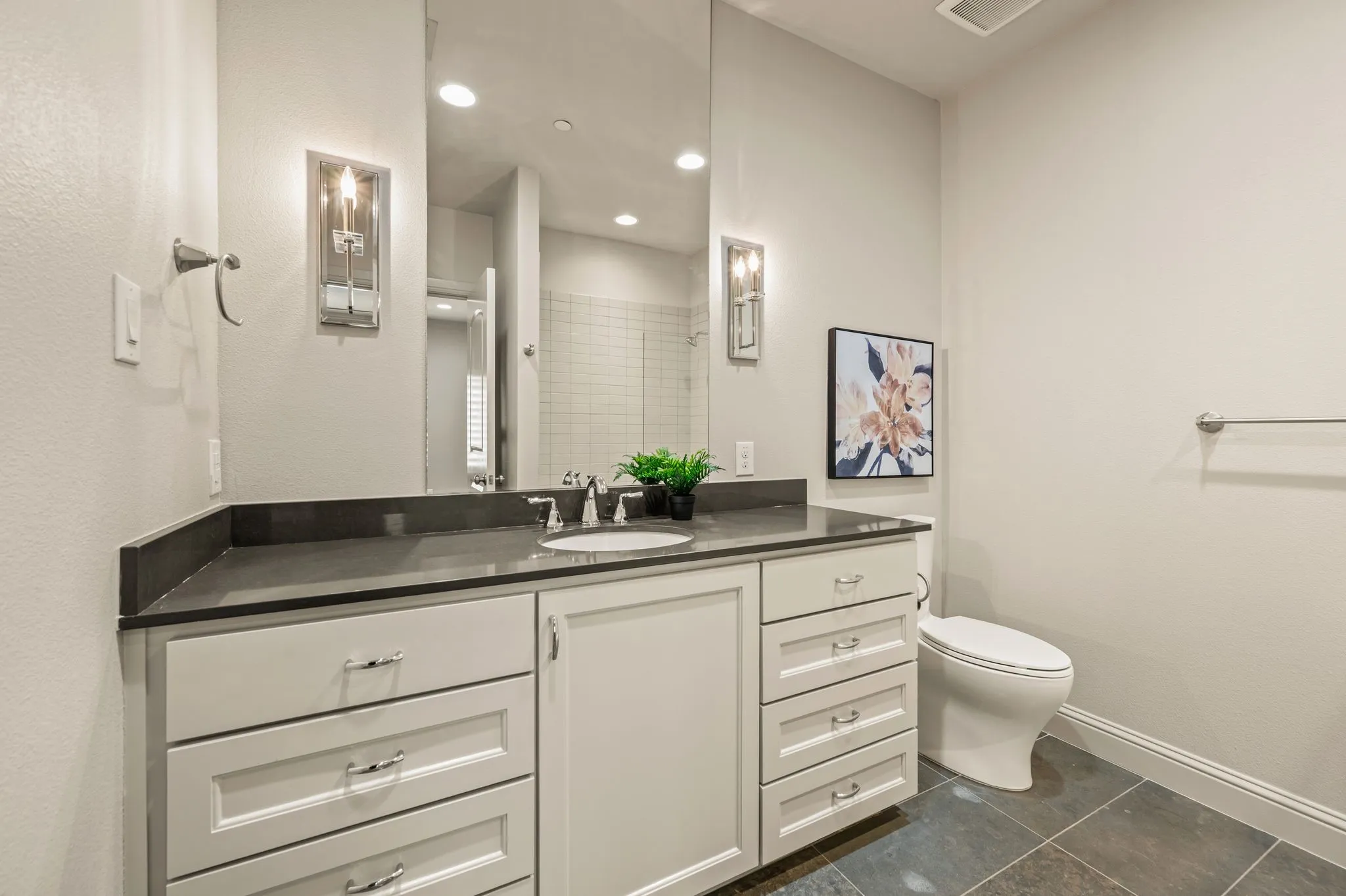 Spacious vanity with a dark countertop, undermount sink, and extensive storage cabinetry