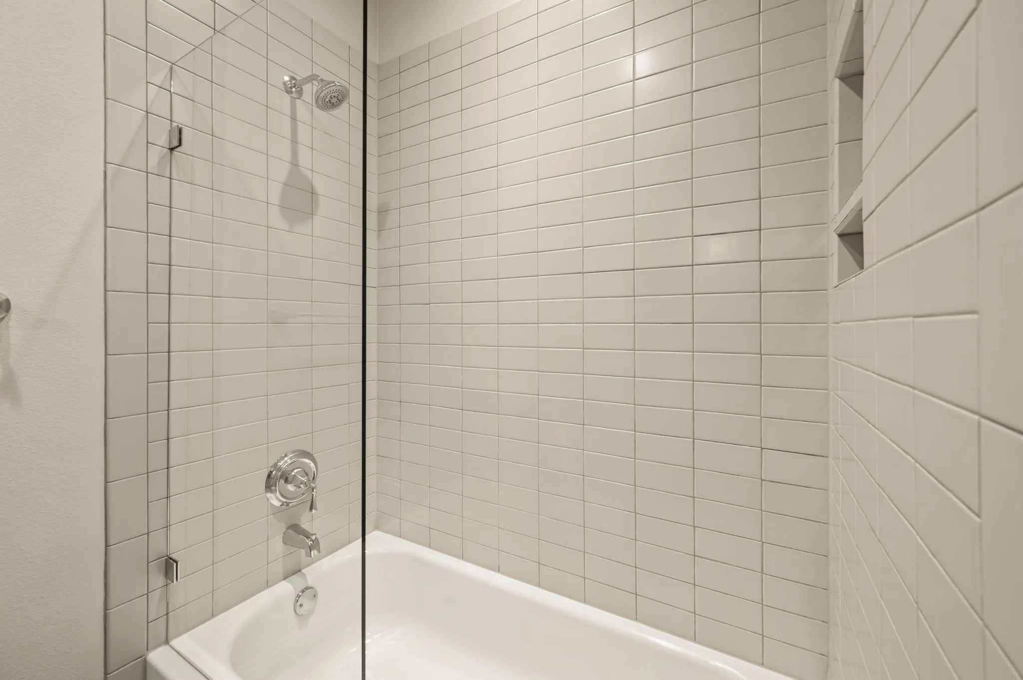 Built-in bathtub with a tile surround and chrome fixtures