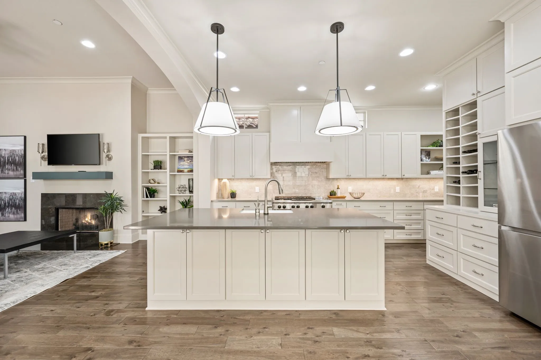 Spacious kitchen with a central island and pendant lighting, white cabinetry, integrated wine storage, and stainless steel appliances
