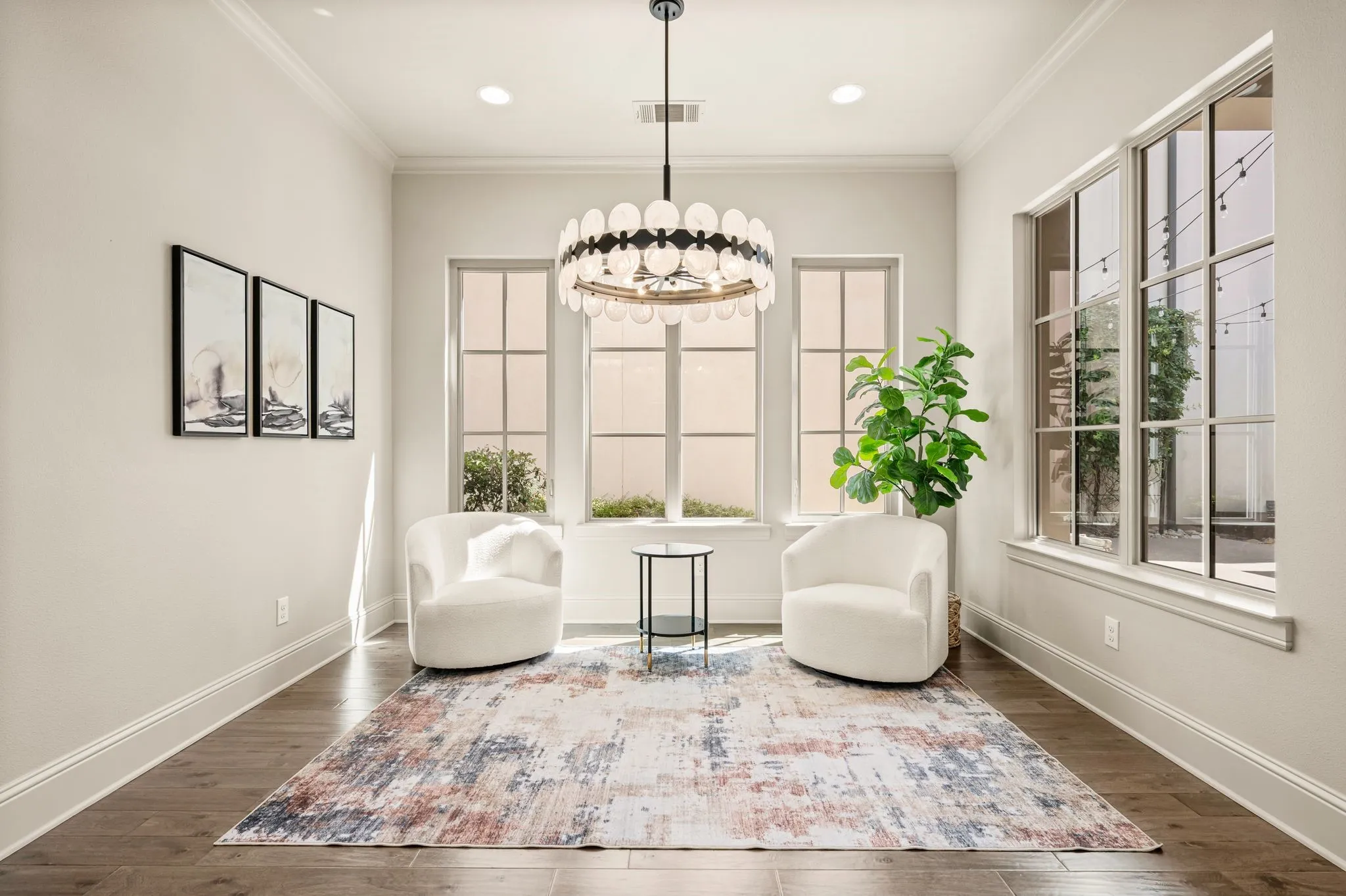 Hardwood flooring, crown molding, abundant natural light, recessed lighting, and a contemporary chandelier